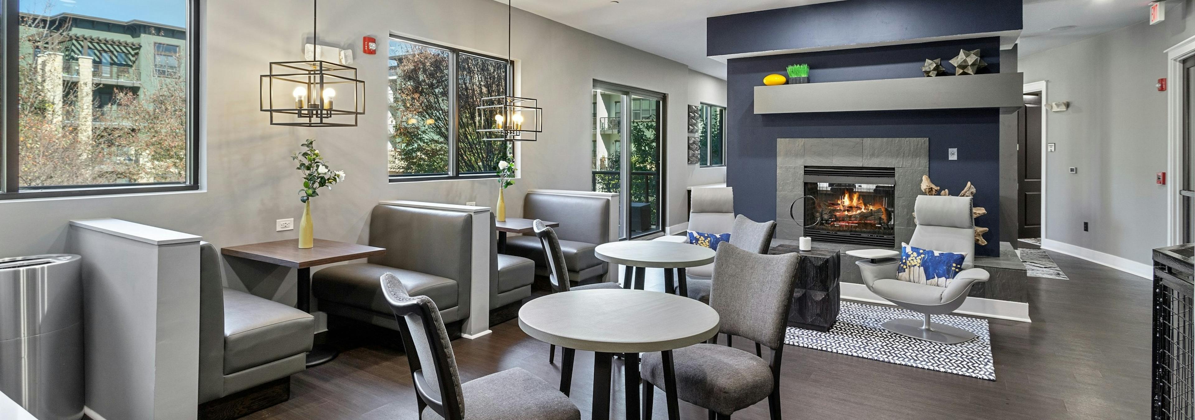 AMLI Parkside cyber café with booth and table and chair seating and wood flooring with a fireplace in the center and windows
