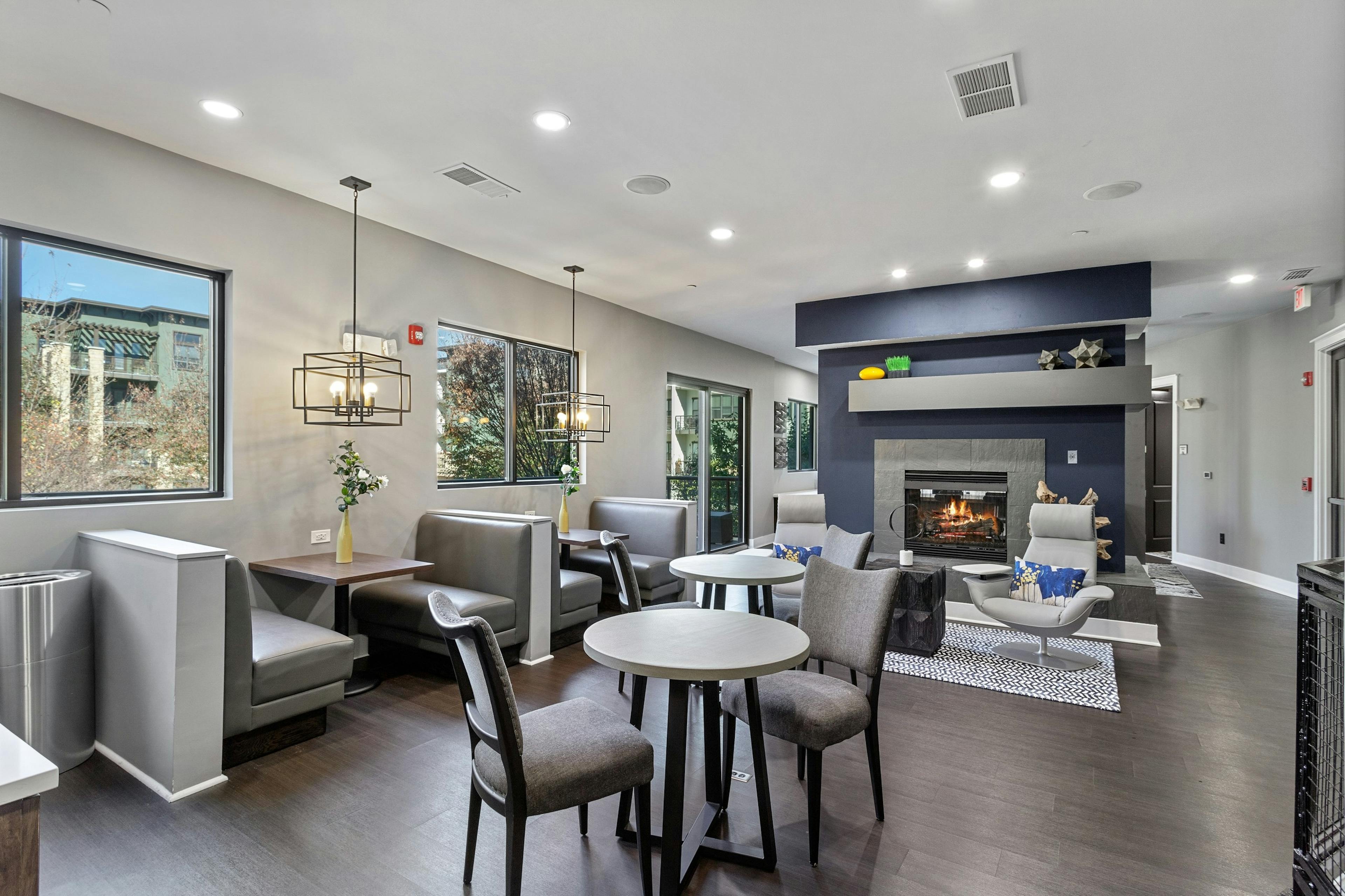 AMLI Parkside cyber café with booth and table and chair seating and wood flooring with a fireplace in the center and windows