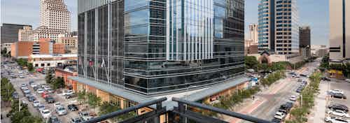 Daytime view of city buildings with busy roads and vibrant trees from balcony at AMLI Downtown apartment community