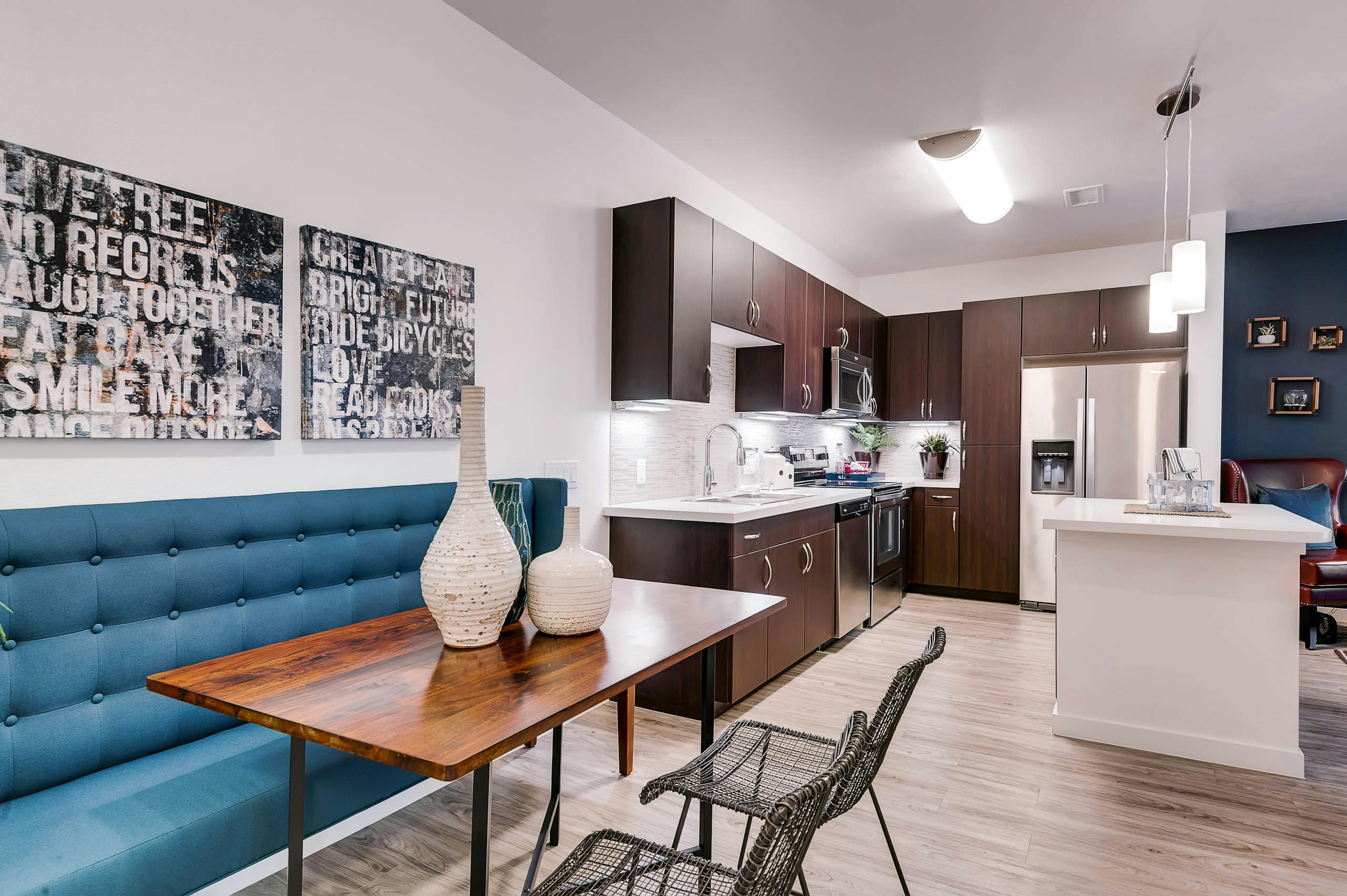 A kitchen and dining room at AMLI Cherry Creek apartments with an island and a dining room table and artwork on the wall