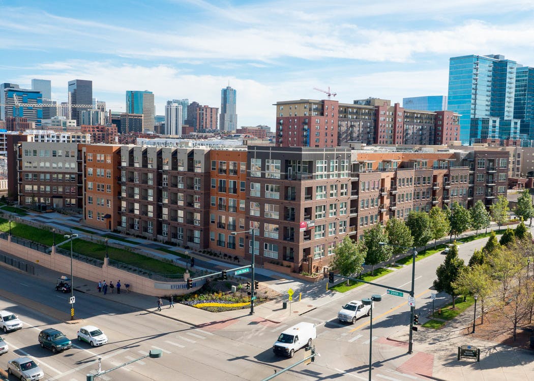 Ariel view of AMLI Riverfront Park apartments with the downtown Denver skyline and the Denver skate park and green trees