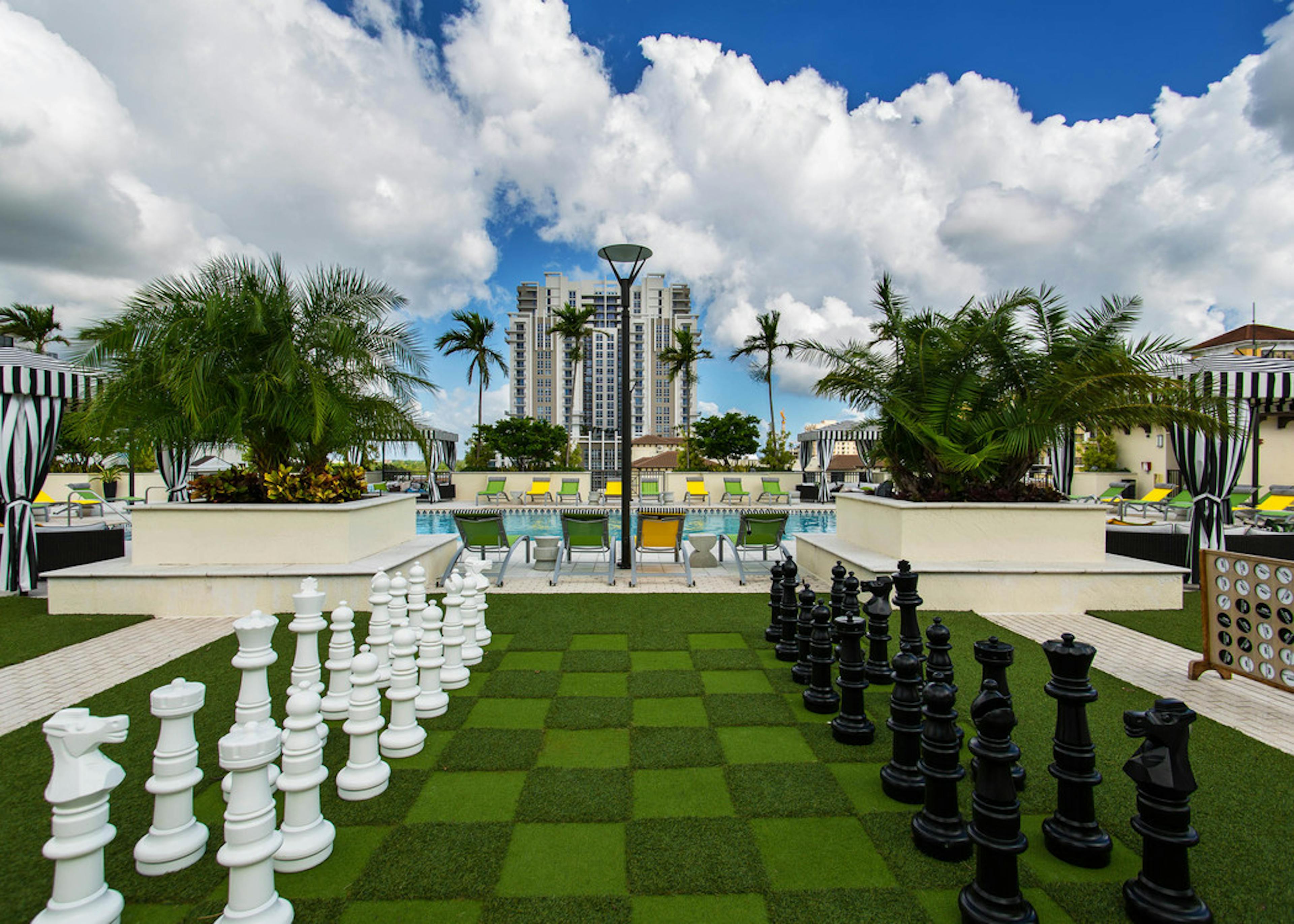 Game view of AMLI Dadeland Rooftop with life sized chess game and a view of the pool and lounge chairs