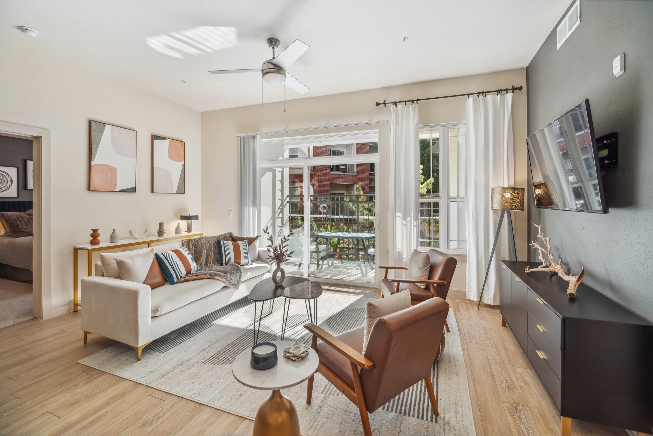 AMLI Park Avenue living room with a large area rug and a couch and 2 chairs as well as a TV and view to the pool