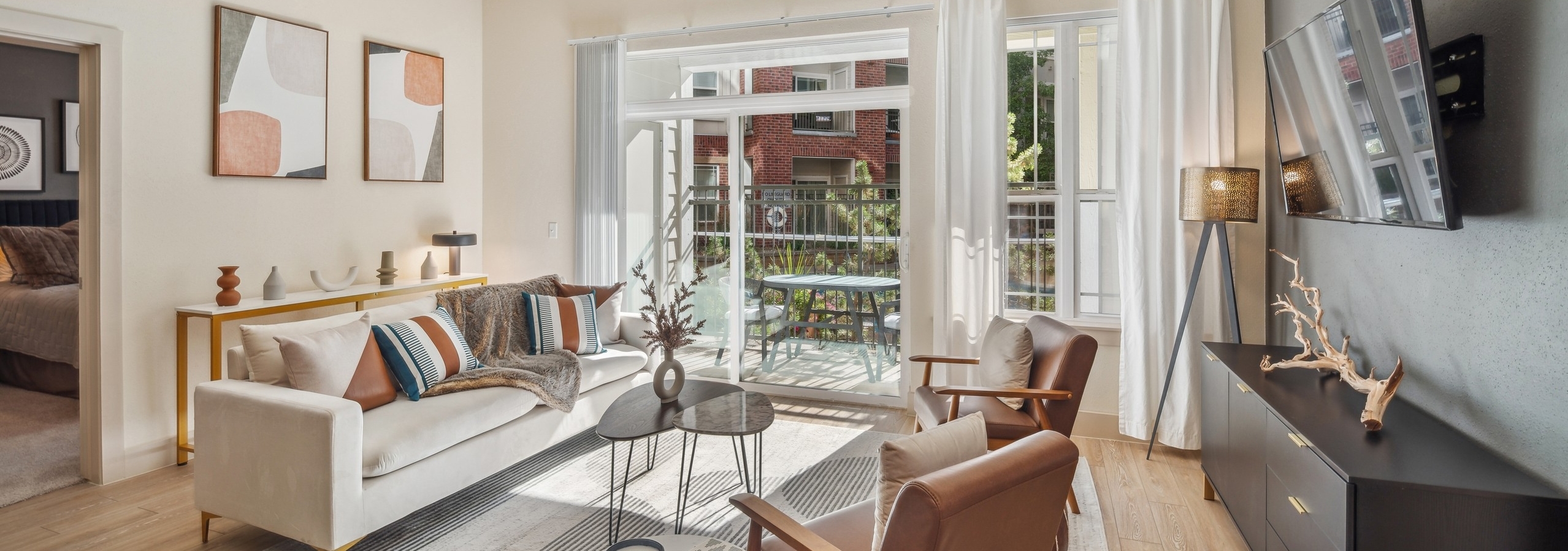 AMLI Park Avenue living room with a large area rug and a couch and 2 chairs as well as a TV and view to the pool