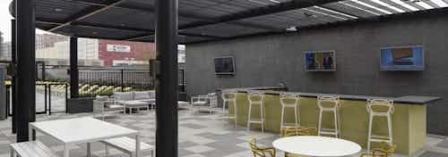 Daytime view of the grill area with available barstool and table seating options at the AMLI Lofts apartment community