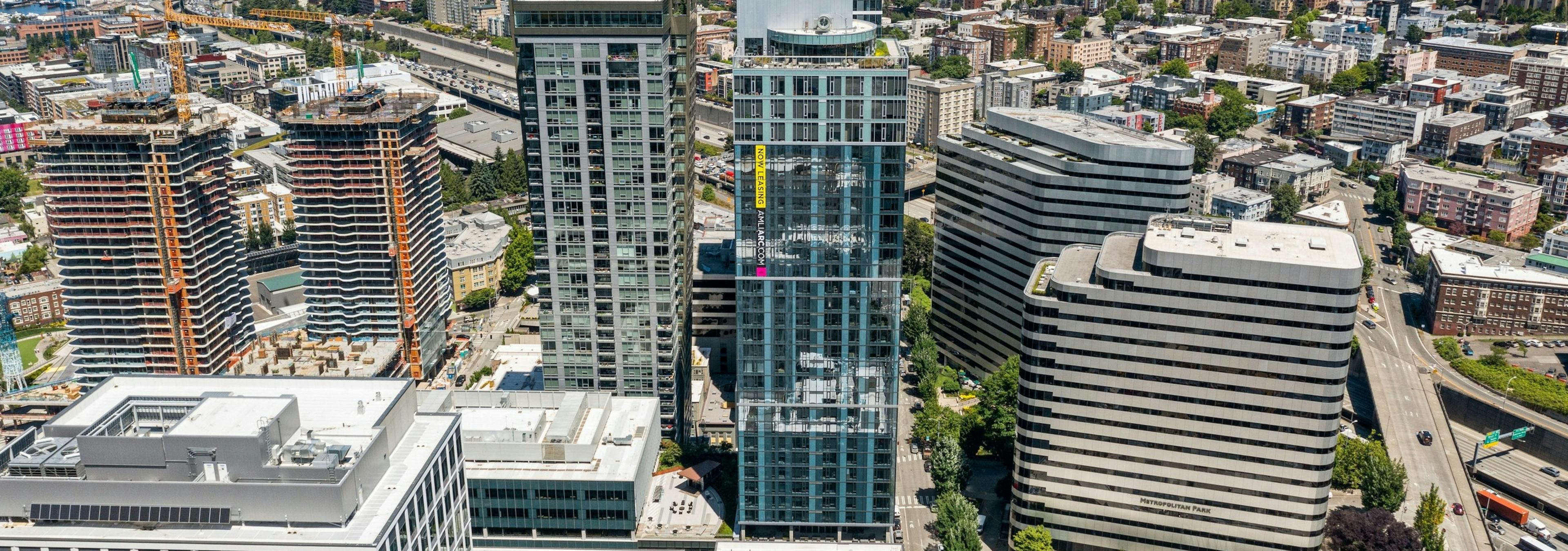 Aerial view of AMLI Arc high rise glass apartment building surrounded by other buildings and view of trees and countless buildings in the distance