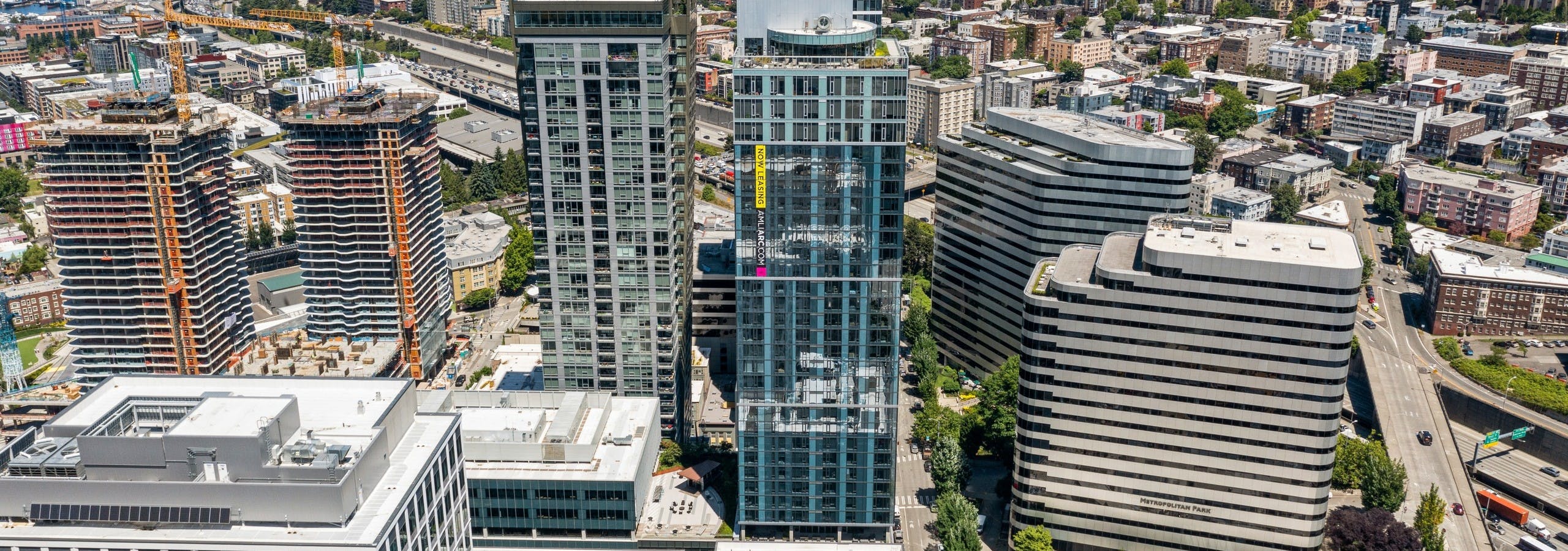 Aerial view of AMLI Arc high rise glass apartment building surrounded by other buildings and view of trees and countless buildings in the distance
