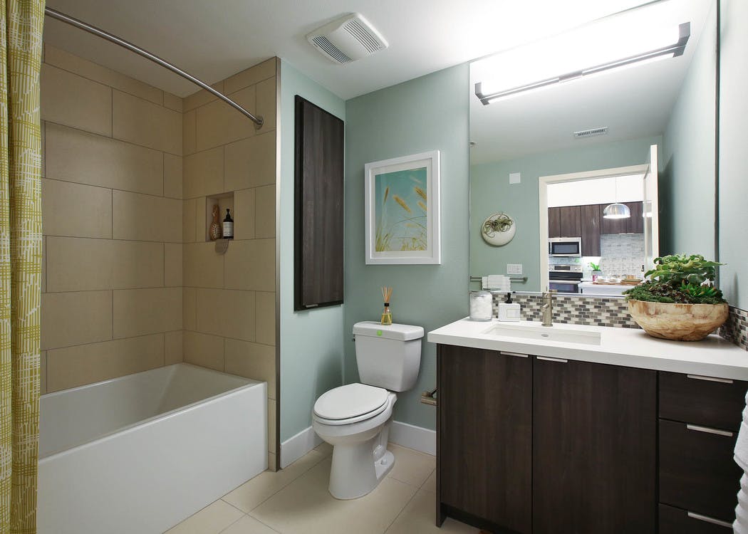 Interior view of AMLI Uptown Orange apartment bathroom with countertop and large soaking tub, tile surround and soap niche