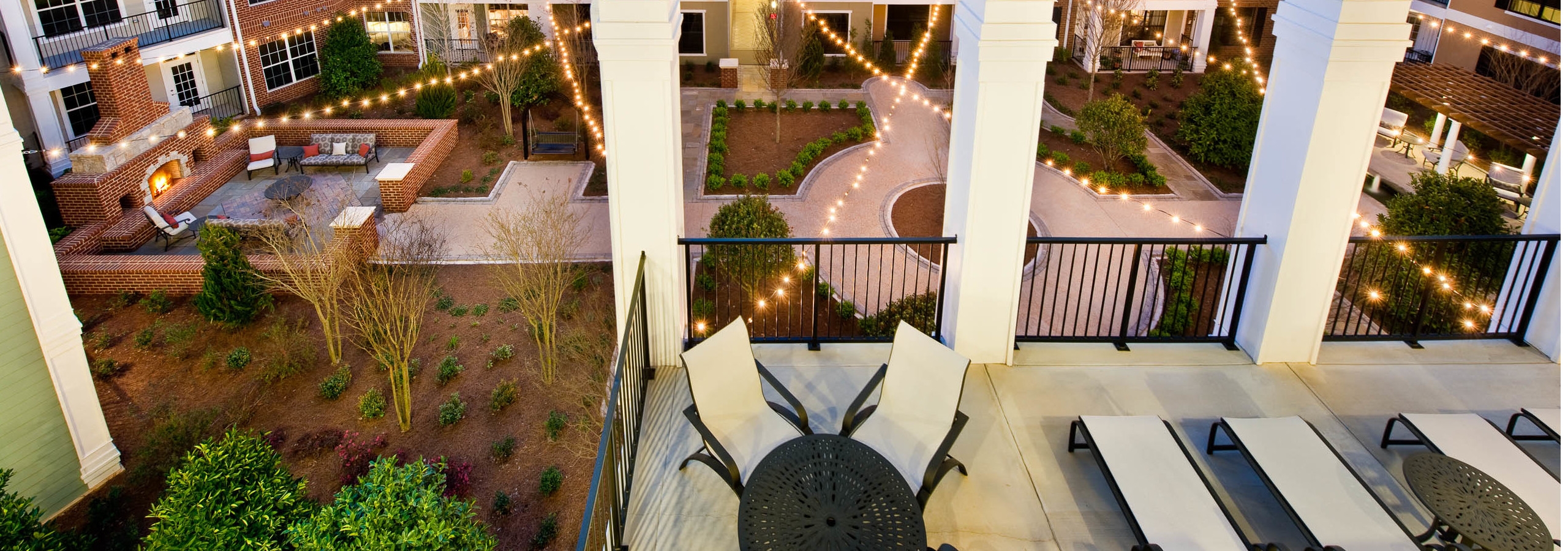 AMLI North Point terrace with a fenced in lounge area with white pillars overlooking the pristine courtyard at nighttime