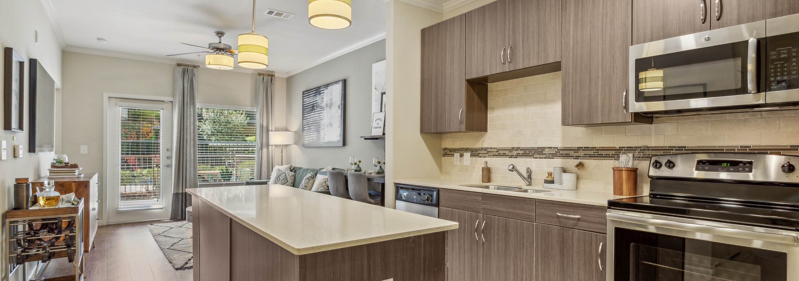 AMLI Ponce Park island kitchen showcasing stainless steel appliances nested in brown cabinets with white tile backsplash