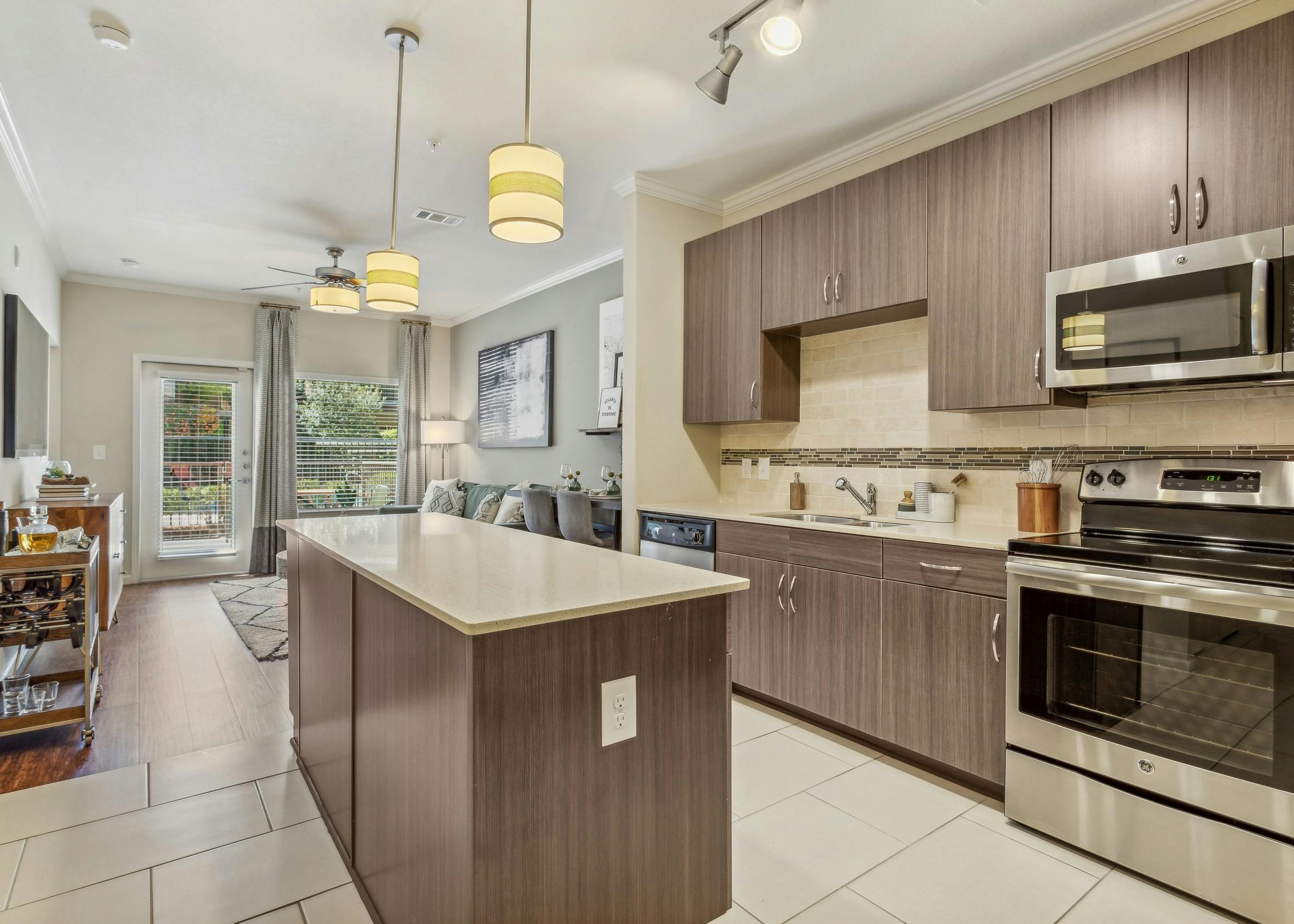 AMLI Ponce Park island kitchen showcasing stainless steel appliances nested in brown cabinets with white tile backsplash
