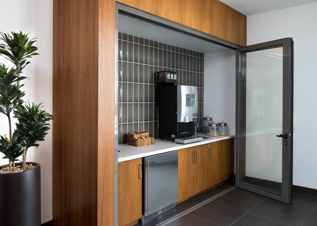 Interior of Starbucks java bar at AMLI Uptown Orange apartments with accordion door and gray tile backsplash and small fridge