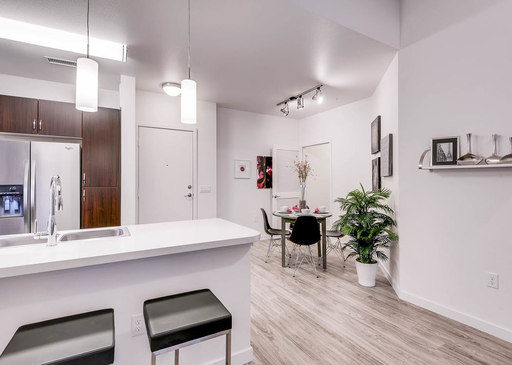A view of a kitchen and dining room at AMLI Cherry Creek apartment with white walls and a small dining table and a fridge