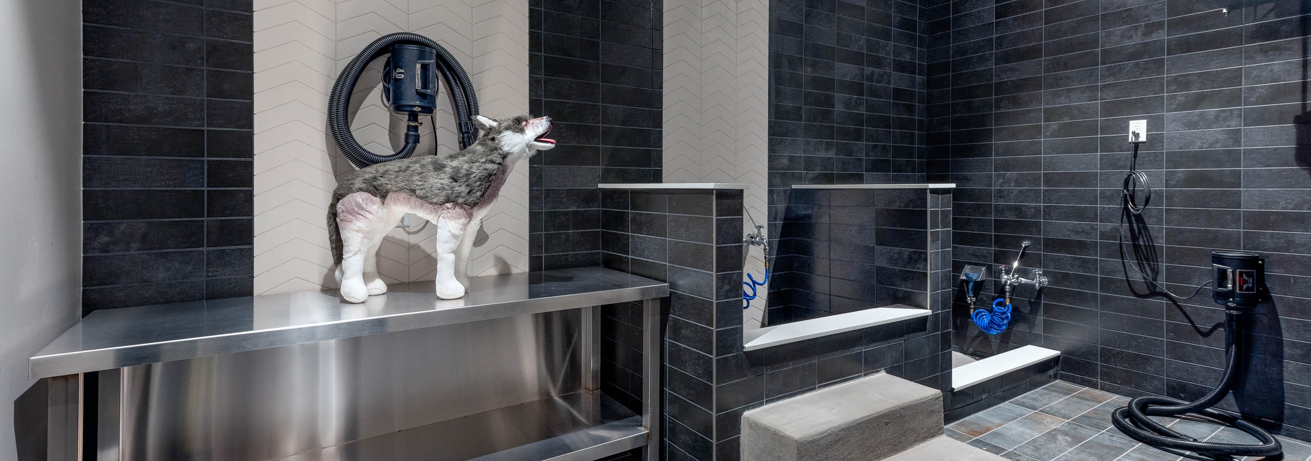 AMLI Art District pet spa with tile throughout and bathing areas with hoses and a large metal table for grooming and drying