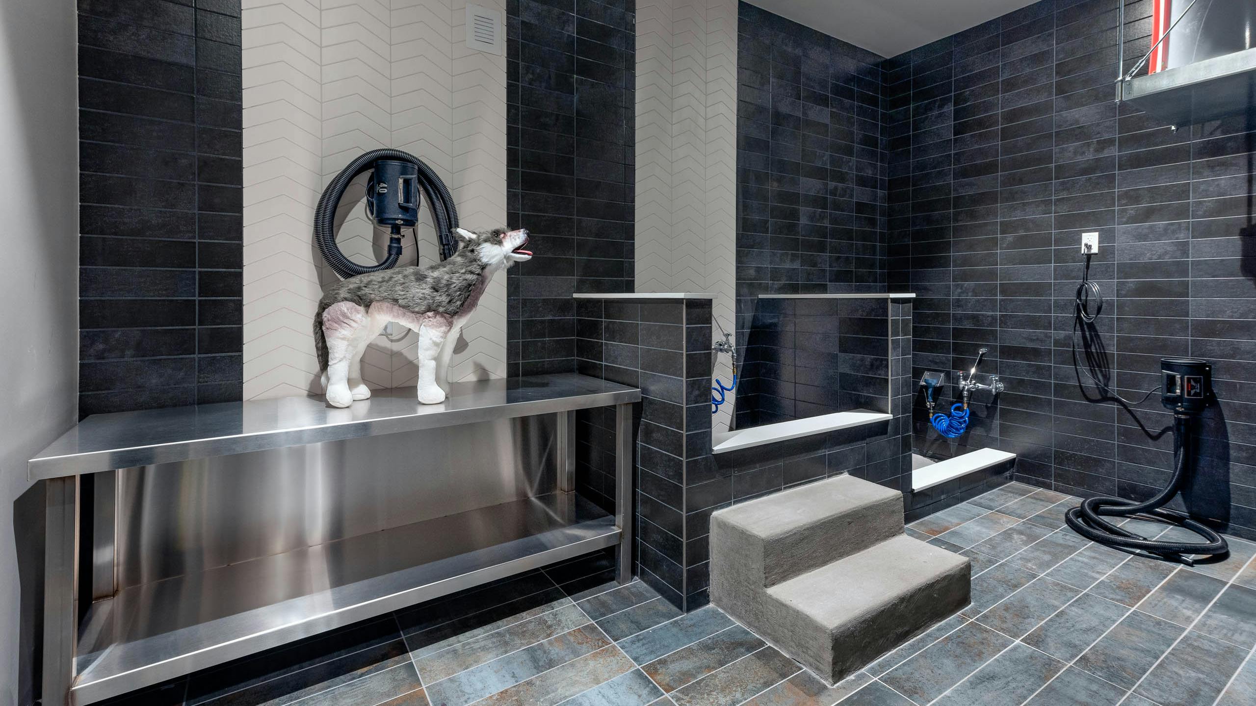 AMLI Art District pet spa with tile throughout and bathing areas with hoses and a large metal table for grooming and drying