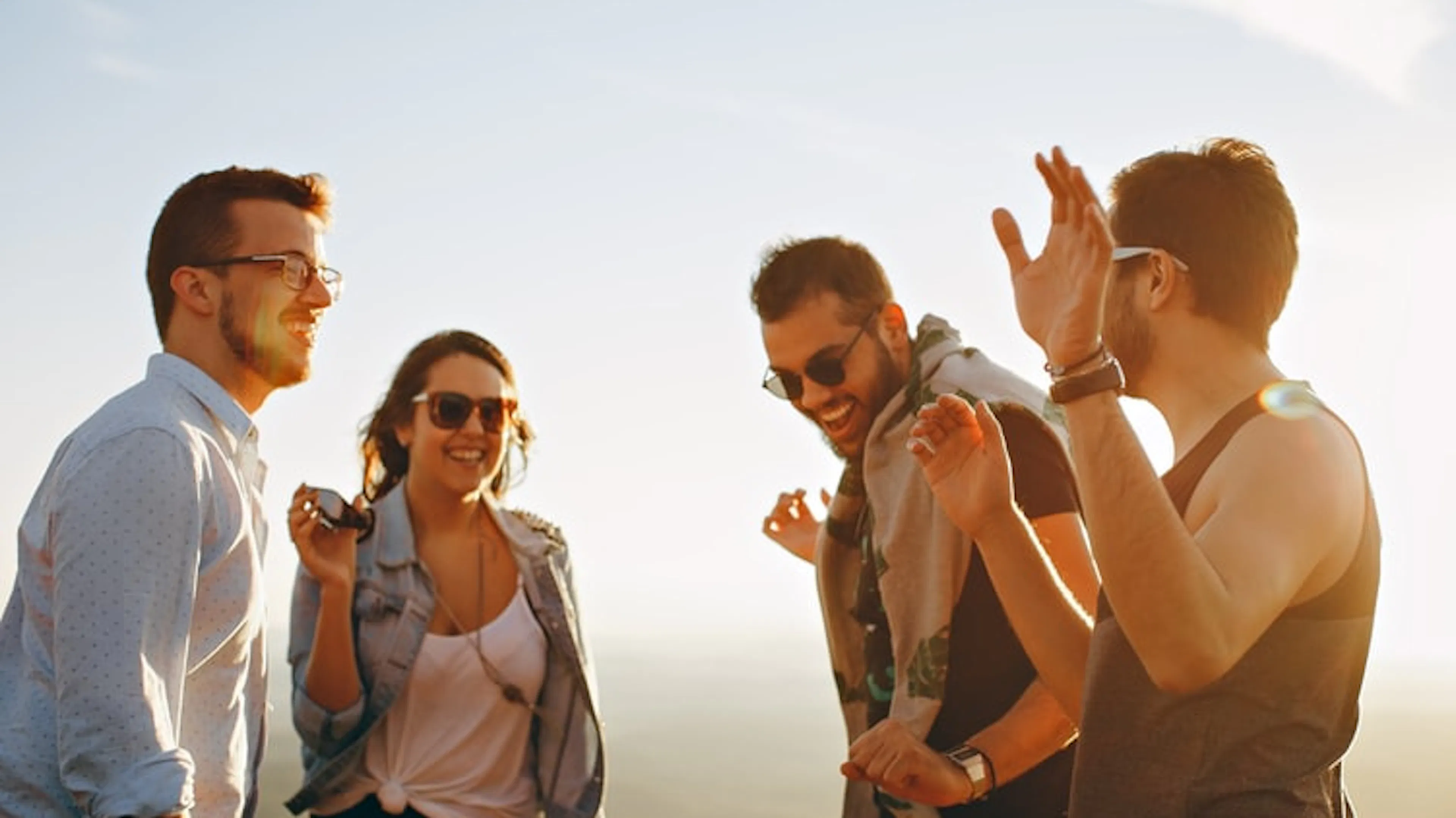 Three men and a woman in sunglasses laughing and talking