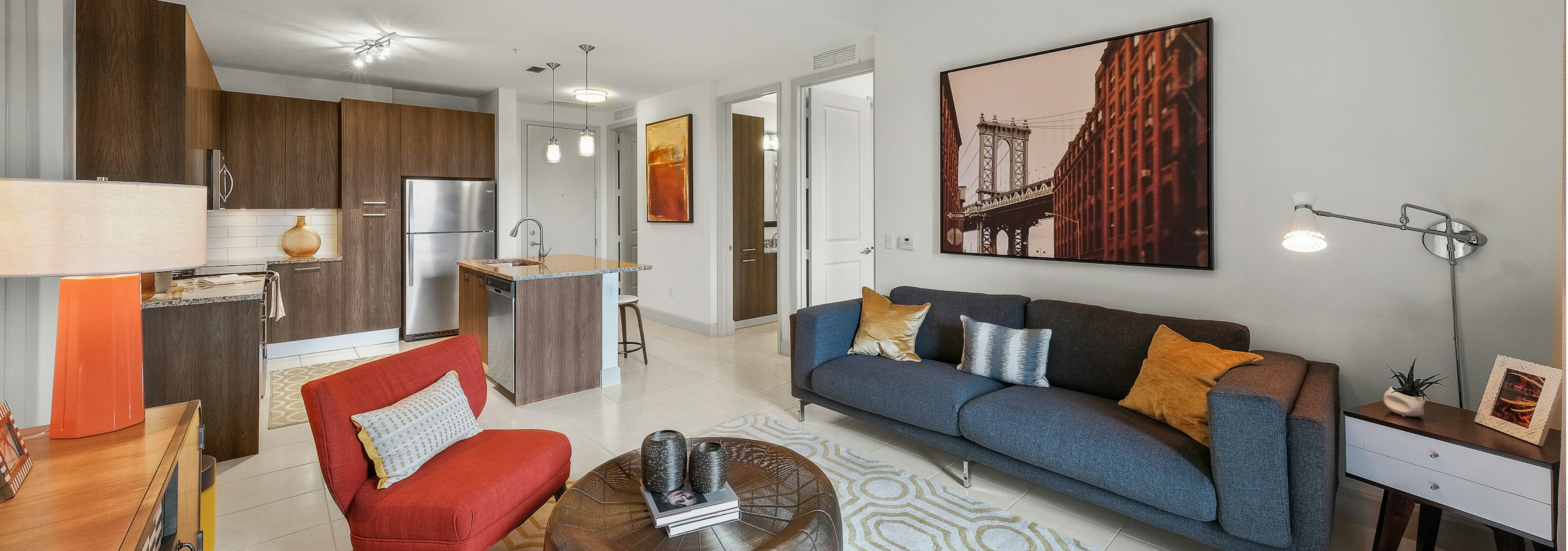  An apartment living room at AMLI 8800 with vibrant orange and blue contemporary style furniture open floorplan with kitchen 