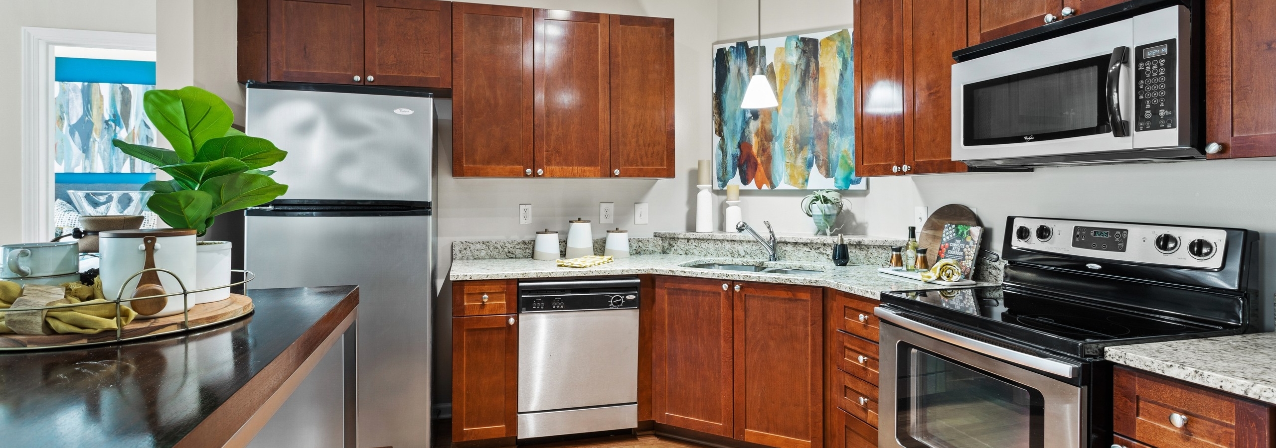 View of the kitchen with wood cabinets and stainless appliances and granite countertops at AMLI Lindbergh apartments