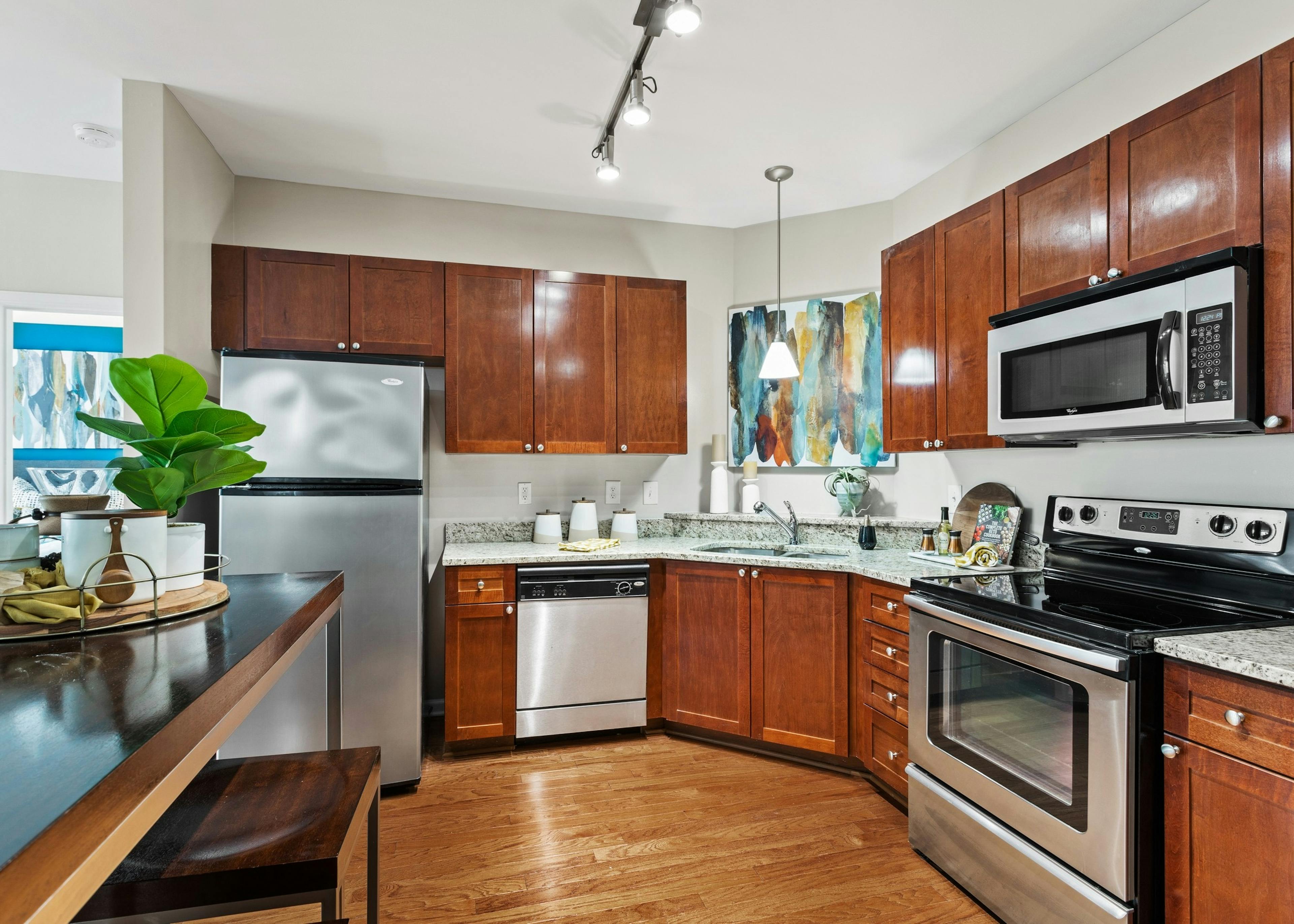 View of the kitchen with wood cabinets and stainless appliances and granite countertops at AMLI Lindbergh apartments