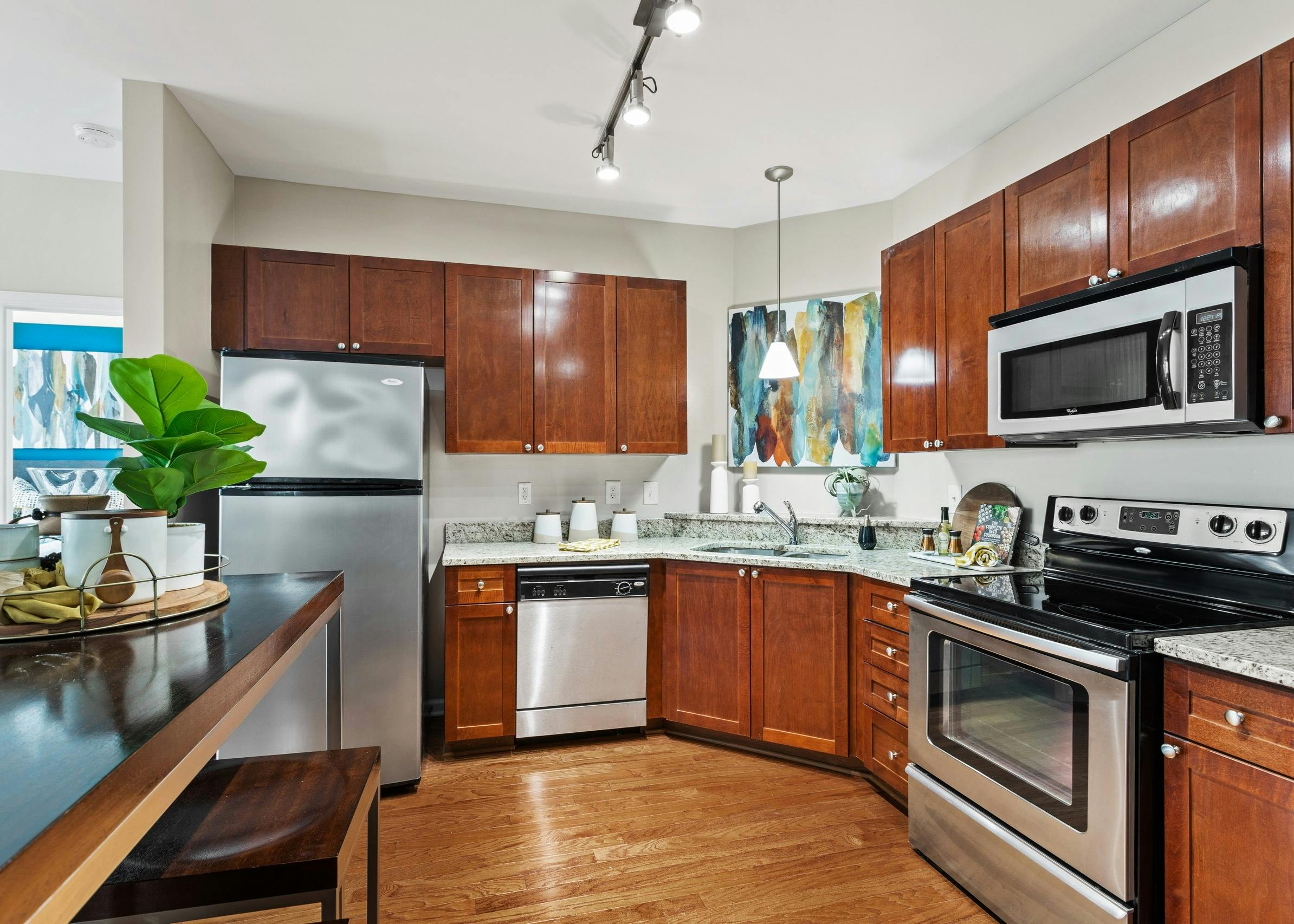 View of the kitchen with wood cabinets and stainless appliances and granite countertops at AMLI Lindbergh apartments