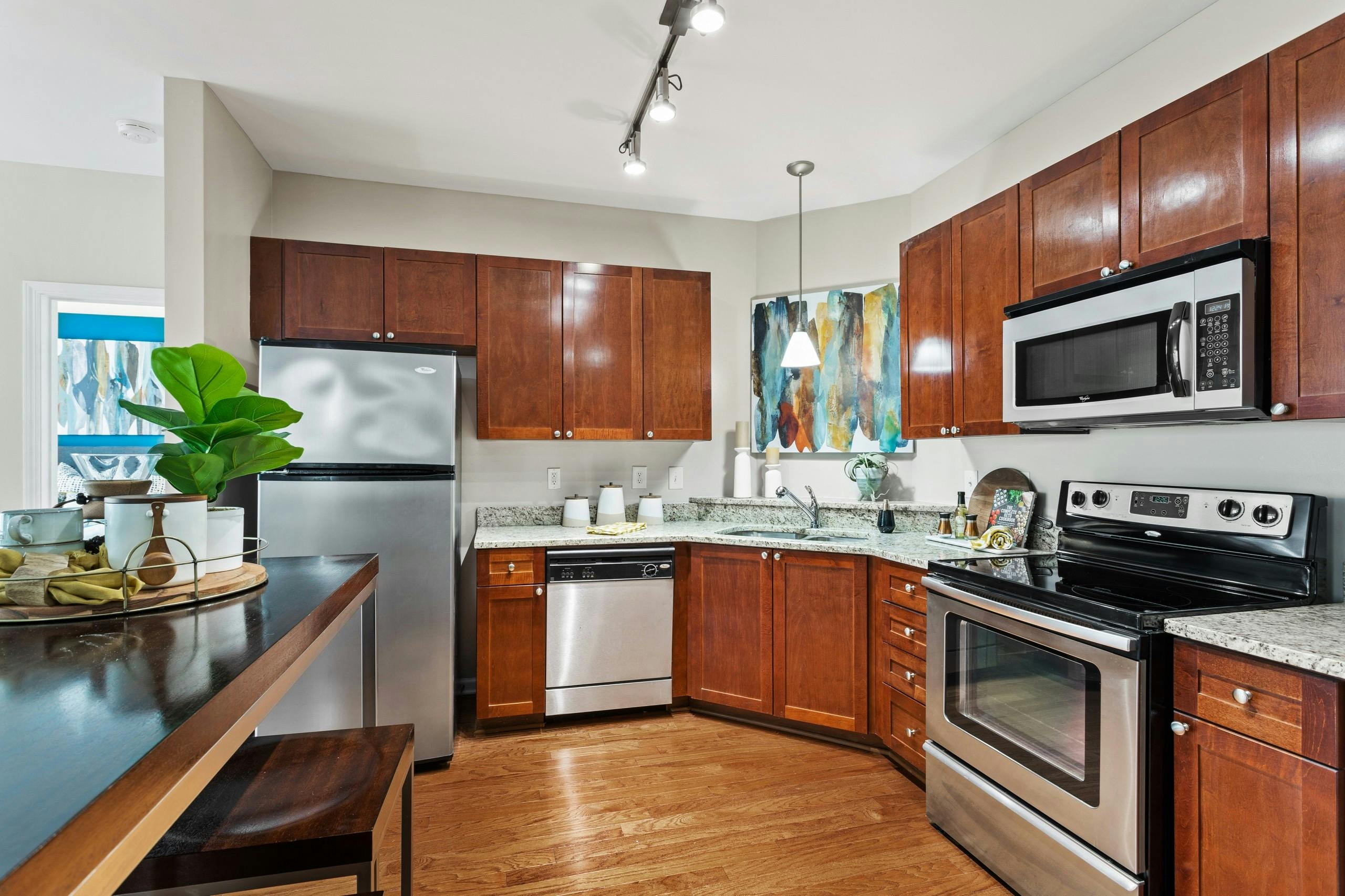 View of the kitchen with wood cabinets and stainless appliances and granite countertops at AMLI Lindbergh apartments