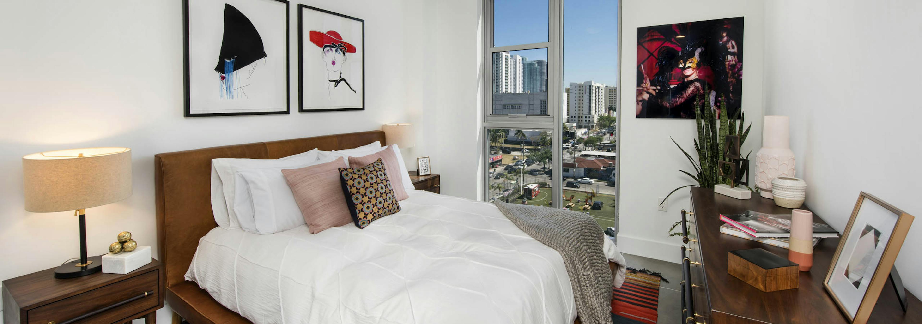 AMLI Midtown 29 bedroom with city view and bed with white bedspread and black and white and red art on the walls with dresser