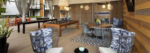 Exterior view of outdoor gaming lanai at AMLI Marina Del Rey apartments with various seating and private covered lounge area