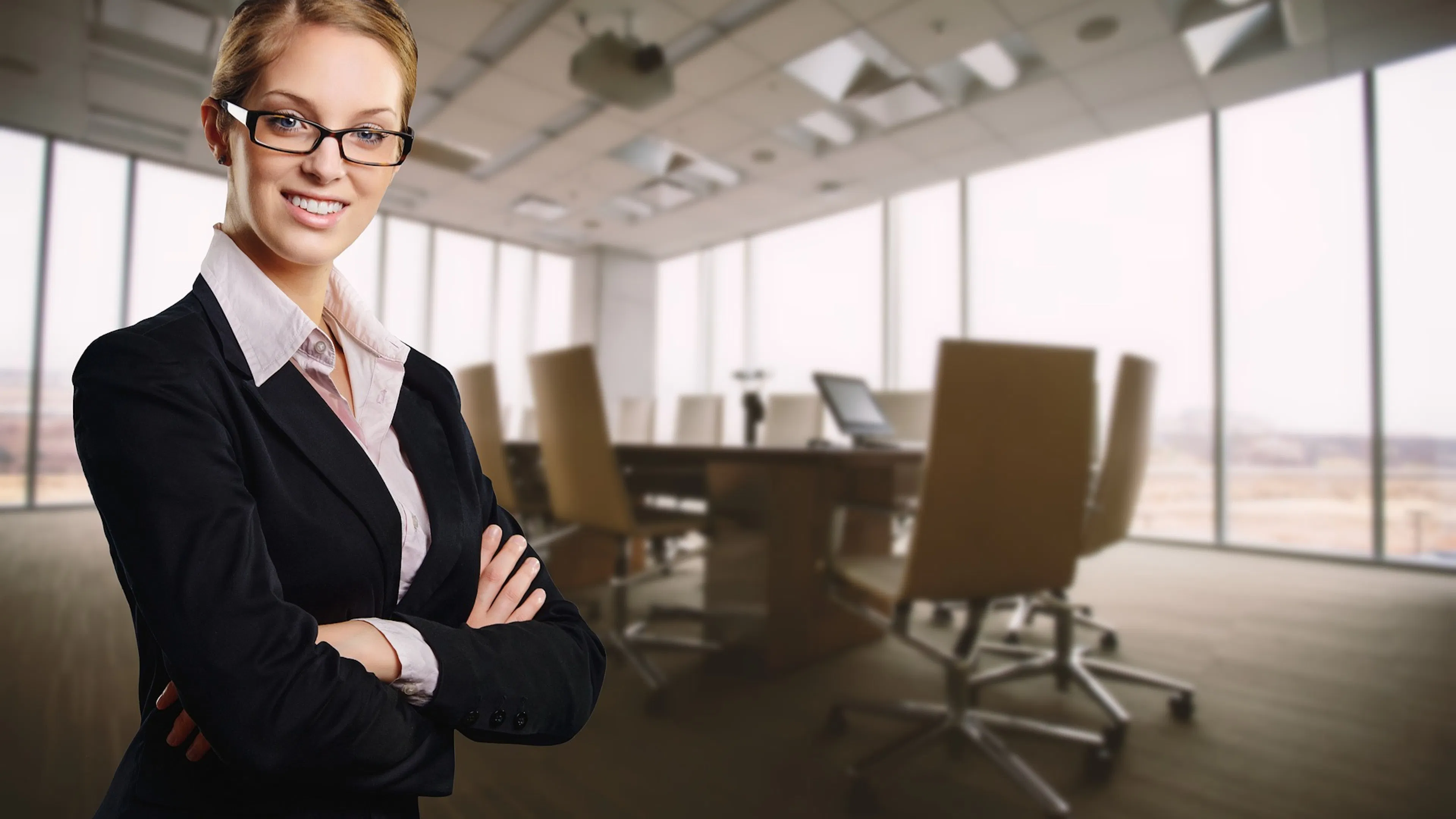 young woman in business suit in front of conference table and windows