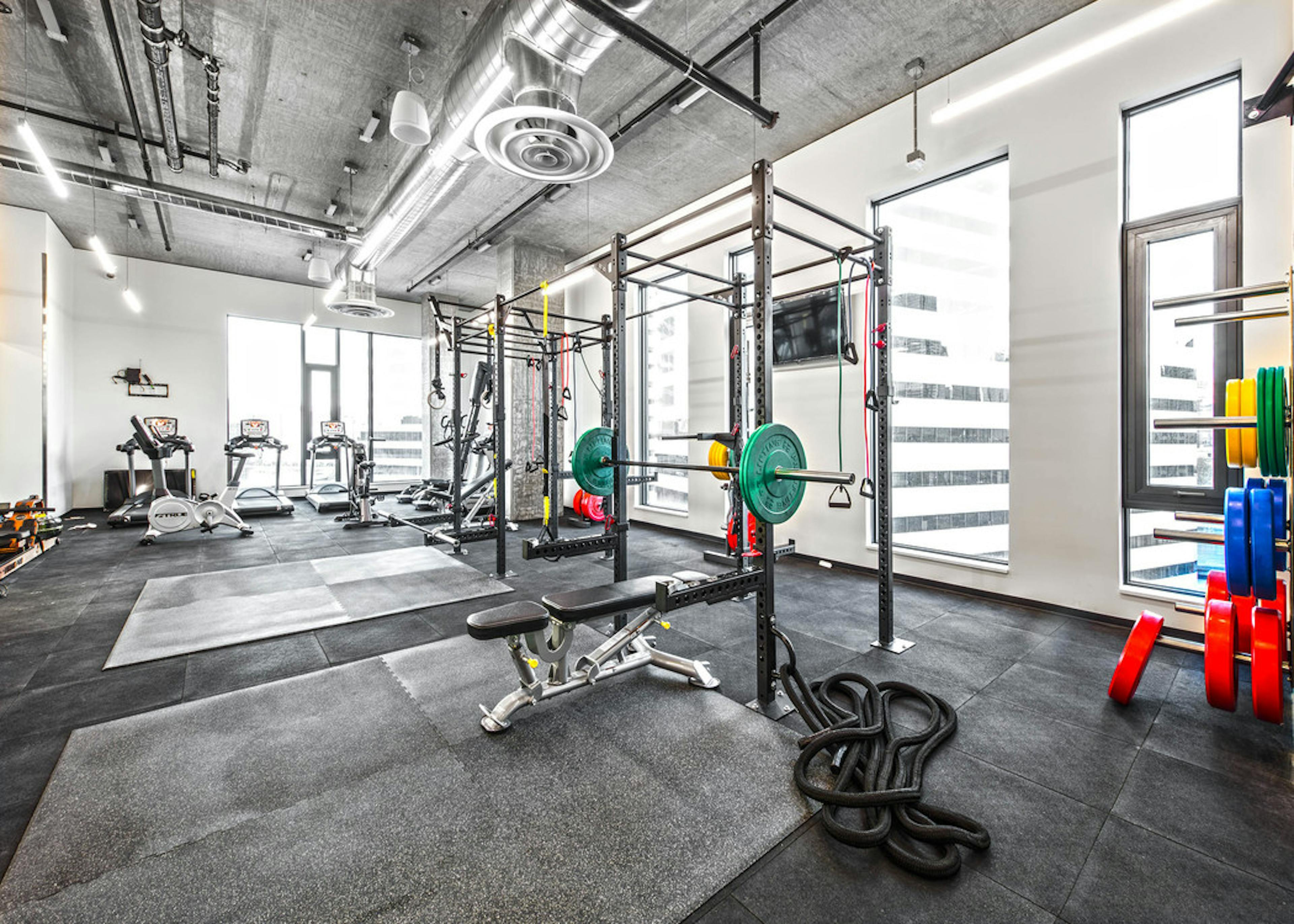 Interior Fitness Center of AMLI Arc with free standing weights squat racks with colorful weights and cardio equipment  