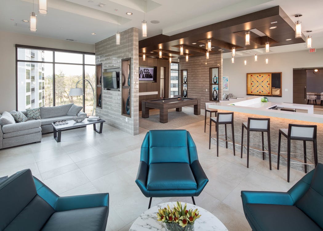 Clubroom at AMLI 3464 with floor to ceiling windows and a variety of seating options with a billiard table and a large TV
