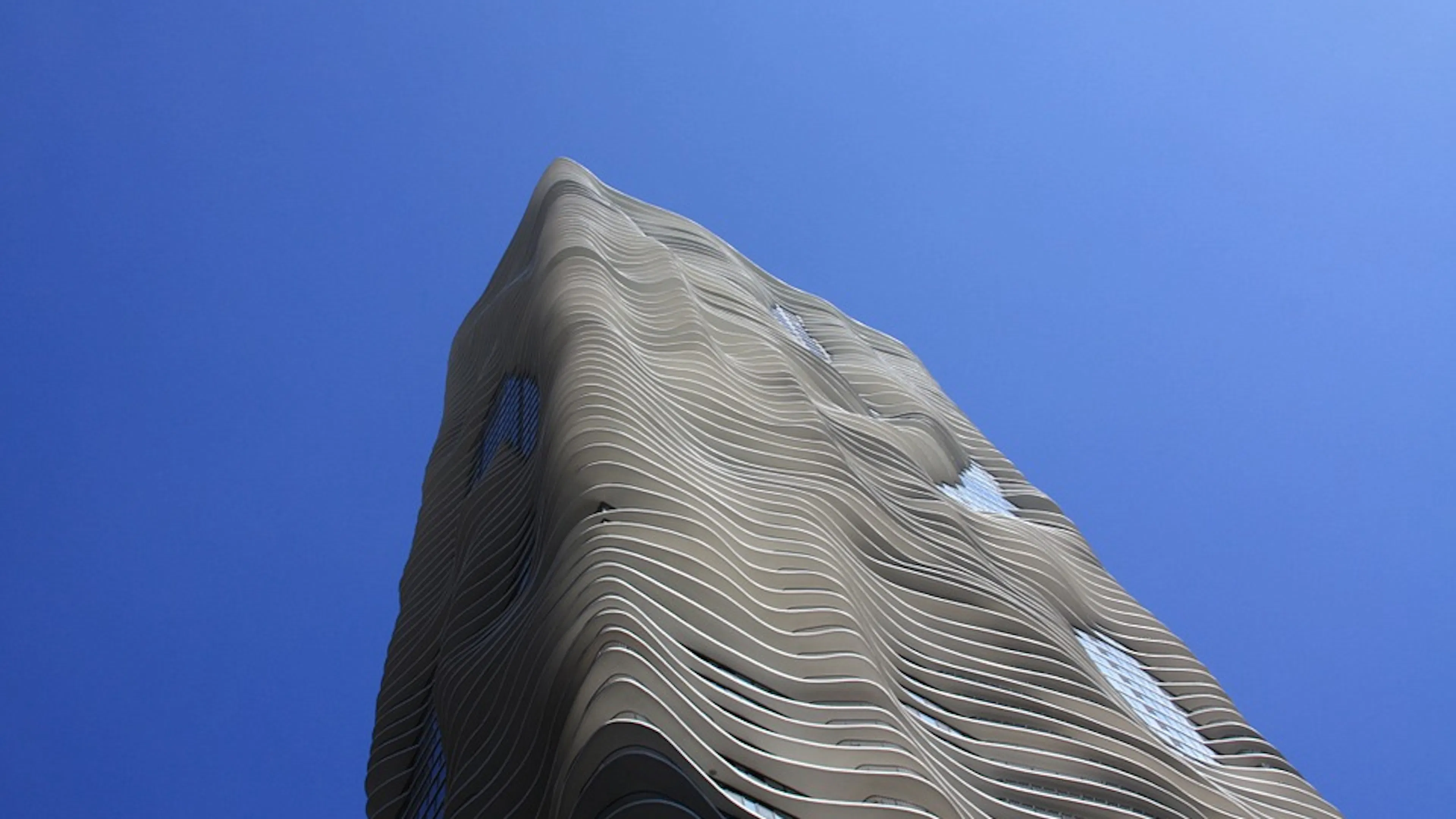 The wavy exterior of the Aqua Tower skyscraper in Chicago against a clear blue sky