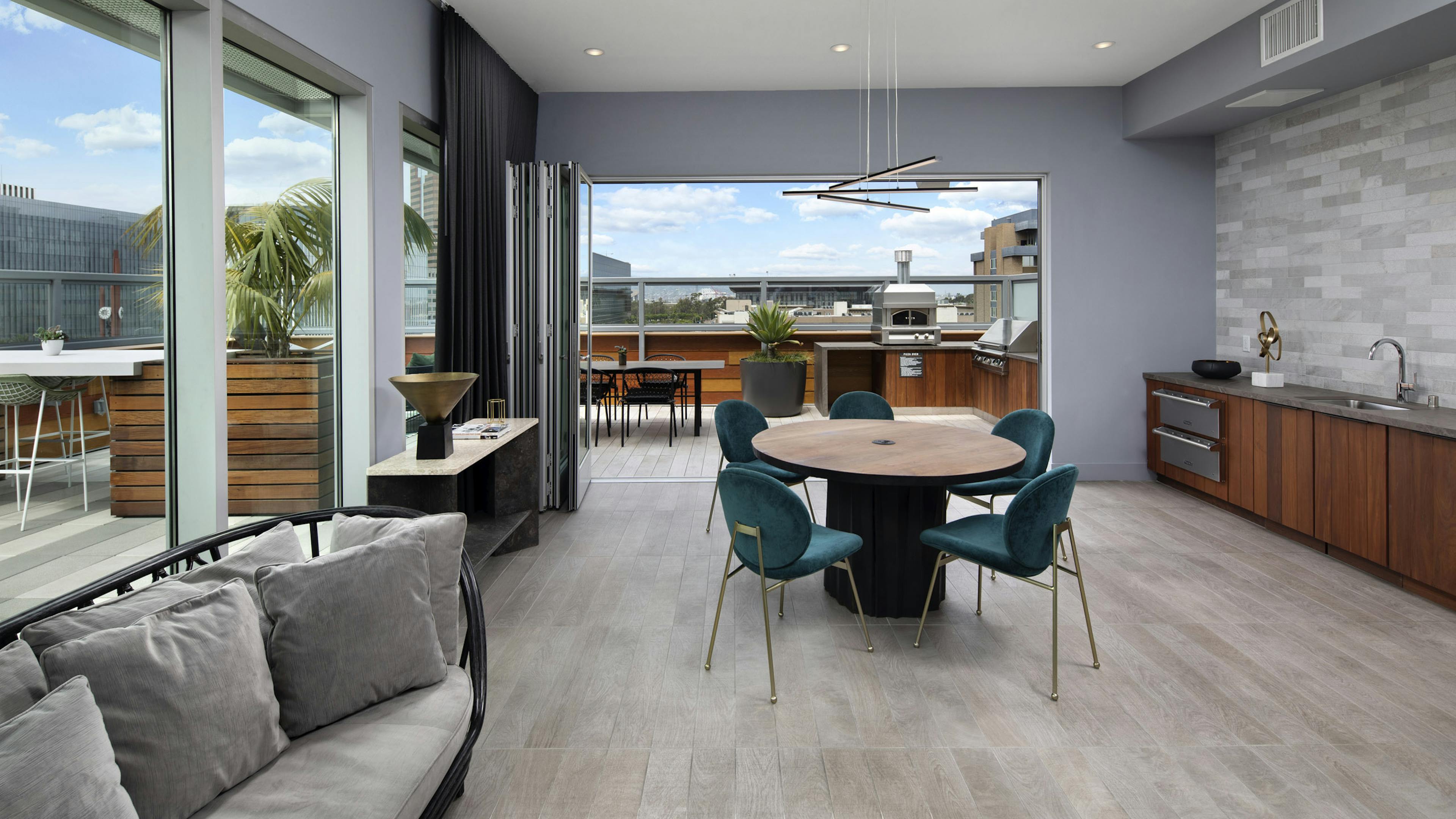 Interior of rooftop lounge with accordion glass doors opened up to the outdoor deck at AMLI Park Broadway apartment building