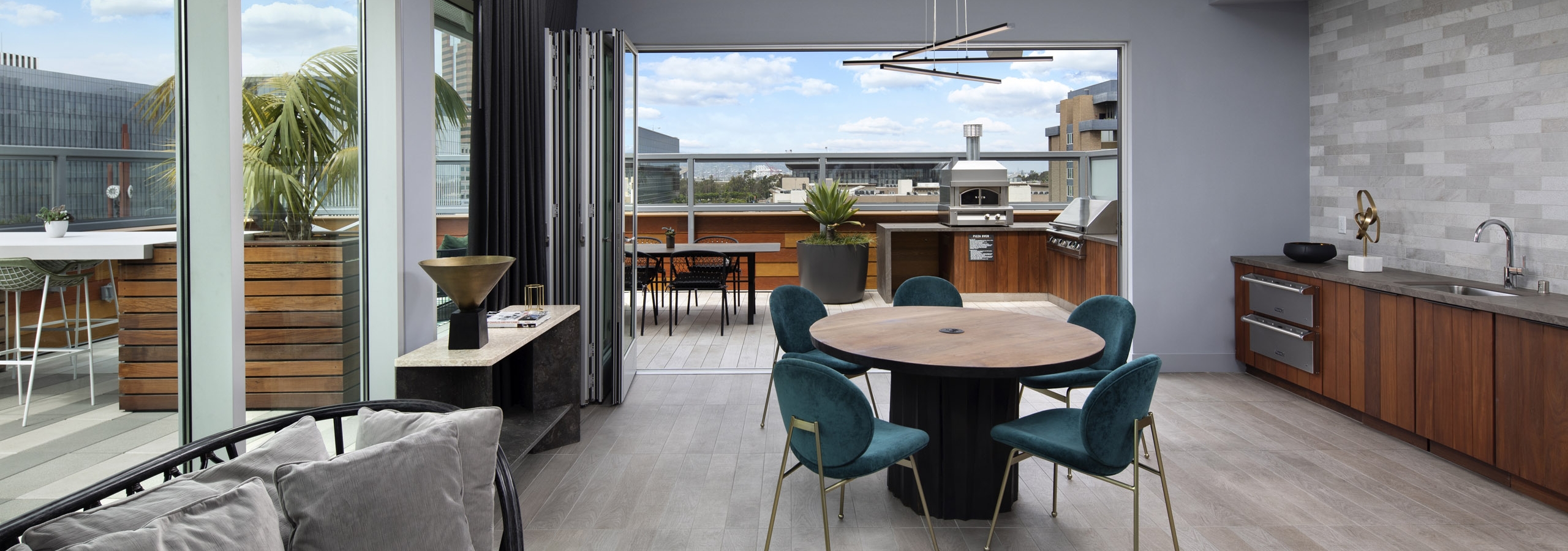 Interior of rooftop lounge with accordion glass doors opened up to the outdoor deck at AMLI Park Broadway apartment building