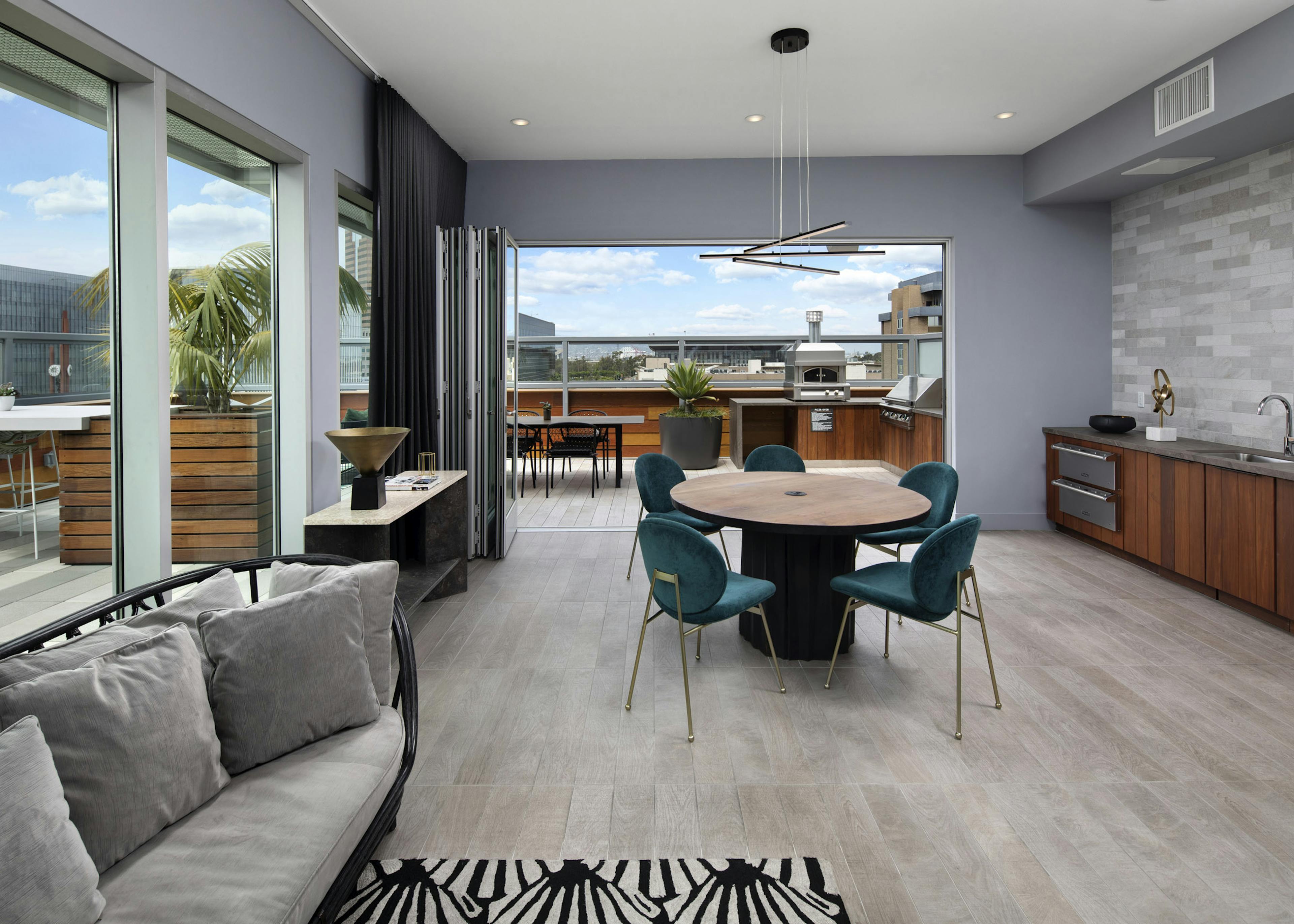 Interior of rooftop lounge with accordion glass doors opened up to the outdoor deck at AMLI Park Broadway apartment building