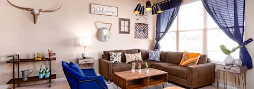 Interior view of a living room at AMLI Arista apartments with a couch and coffee table and a large window with blue curtains
