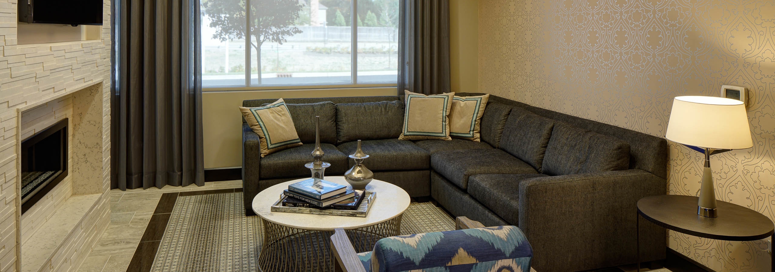 Interior of business center lounge at AMLI Deerfield with a TV and fireplace and a large leather wraparound couch