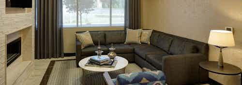 Interior of business center lounge at AMLI Deerfield with a TV and fireplace and a large leather wraparound couch