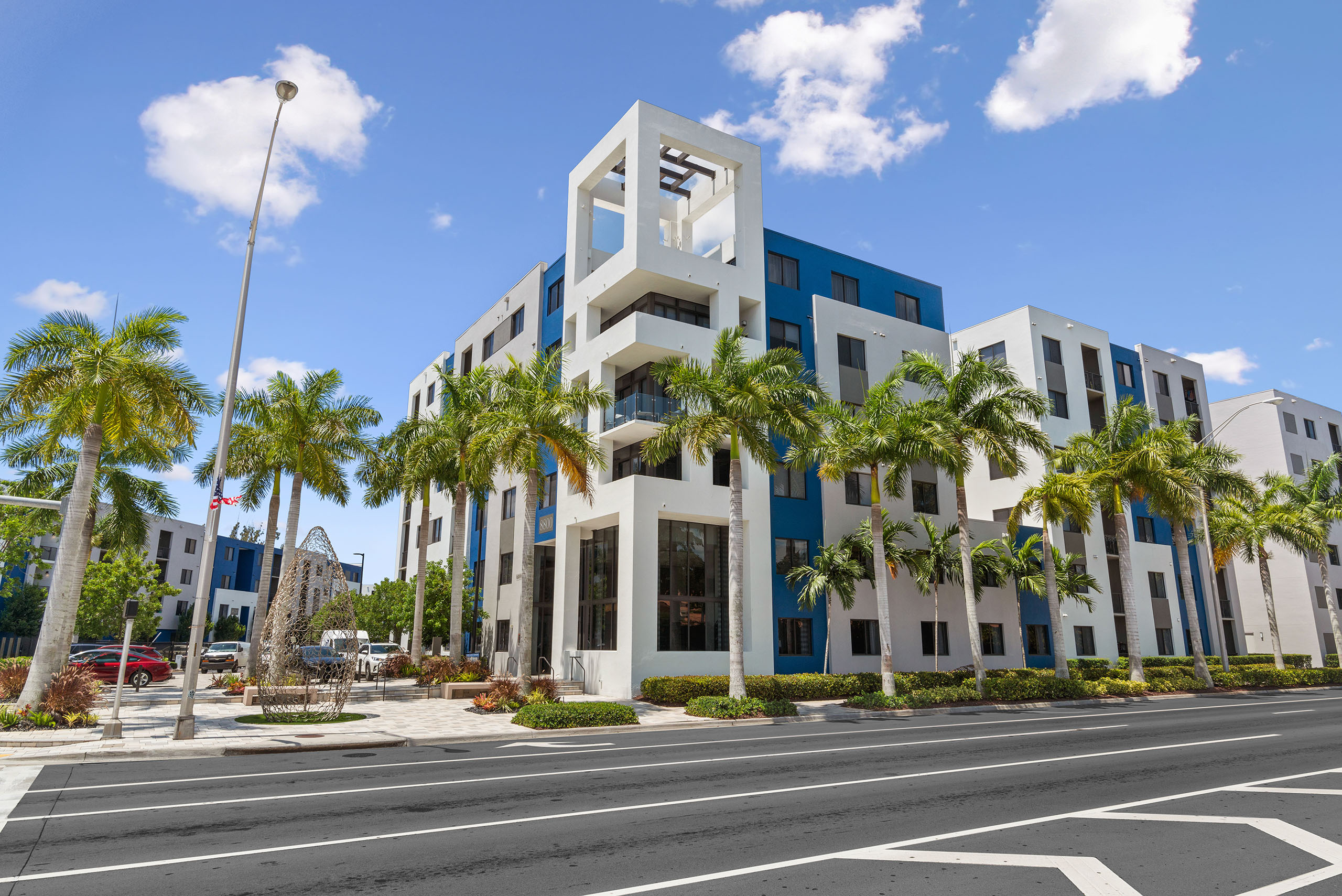 AMLI 8800 apartment building façade with modern design and blue painted accents and wire sculpture and palm trees 