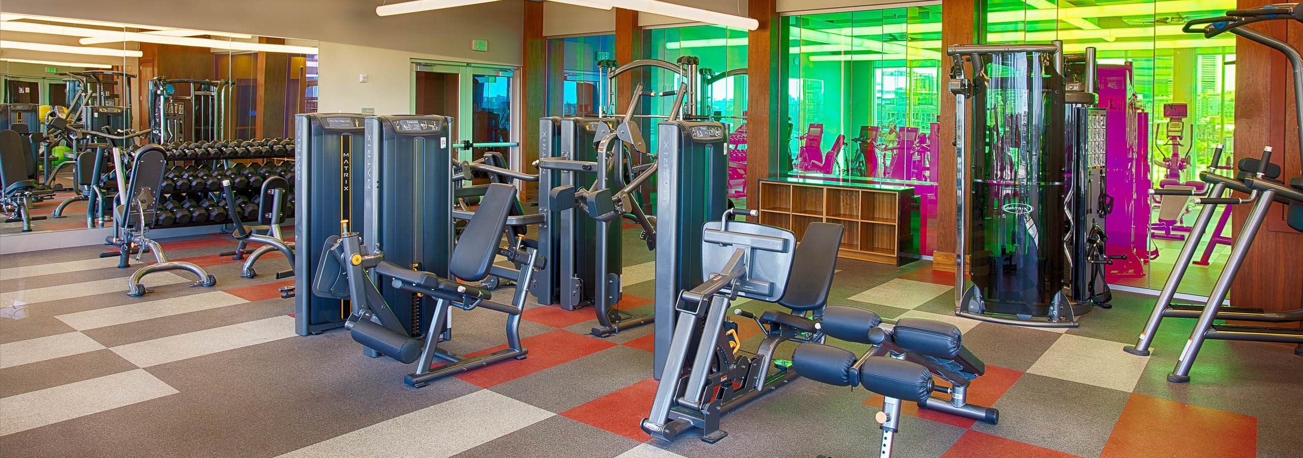 Fitness center at AMLI Denargo Market apartments with multiple strength training machines and free weights and large mirrors