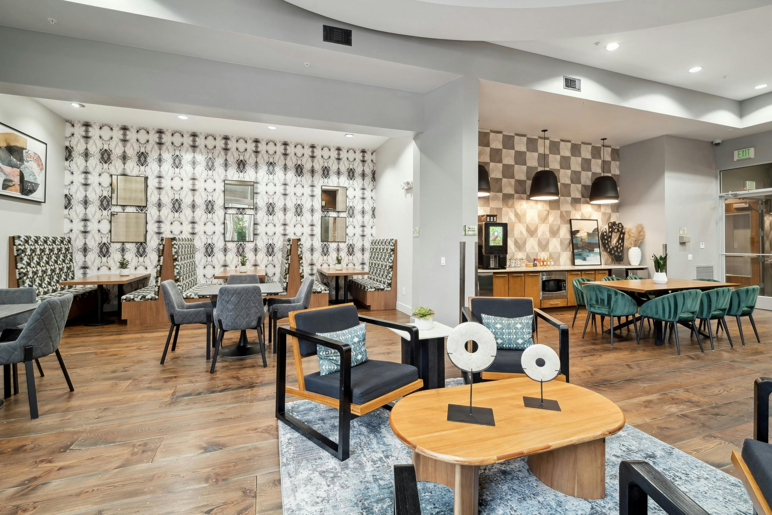 A resident lounge at AMLI RidgeGate with tables and chairs and booths on hardwood flooring and a a coffee machine
