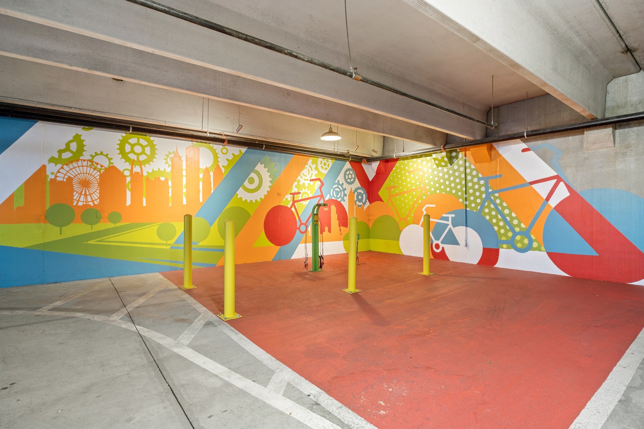 AMLI Ponce Park bike repair area with orange floor and colorful bike mural with green repair station and 4 yellow poles