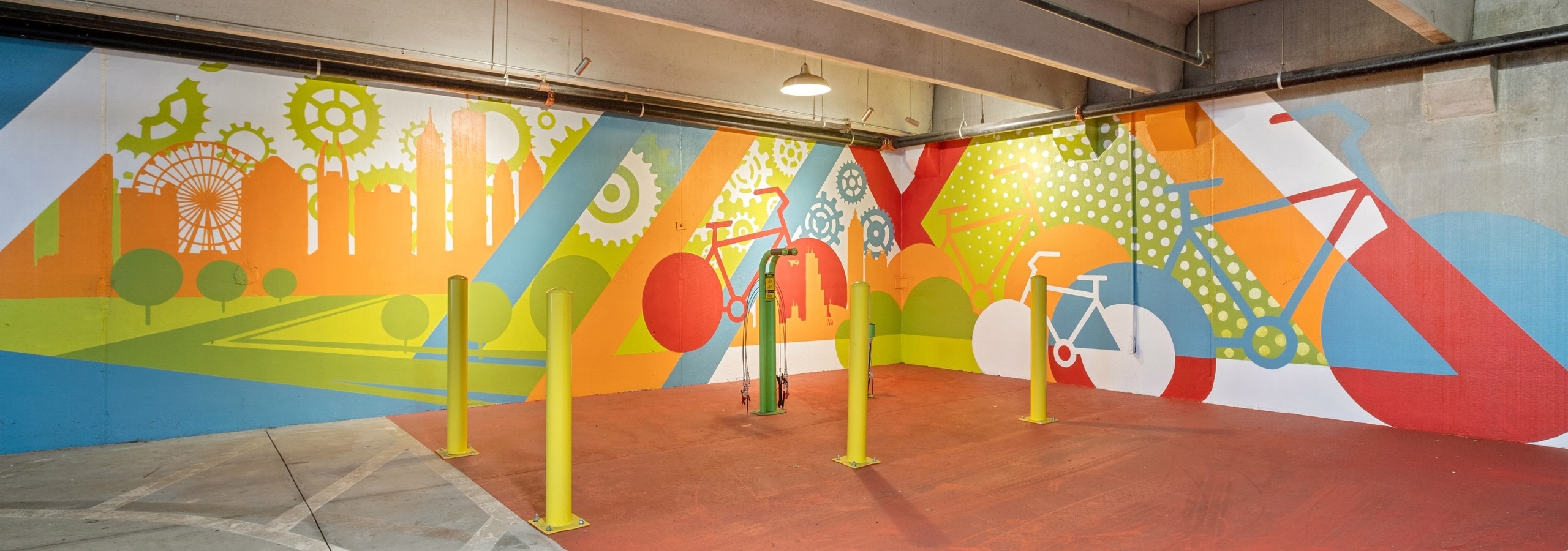 AMLI Ponce Park bike repair area with orange floor and colorful bike mural with green repair station and 4 yellow poles
