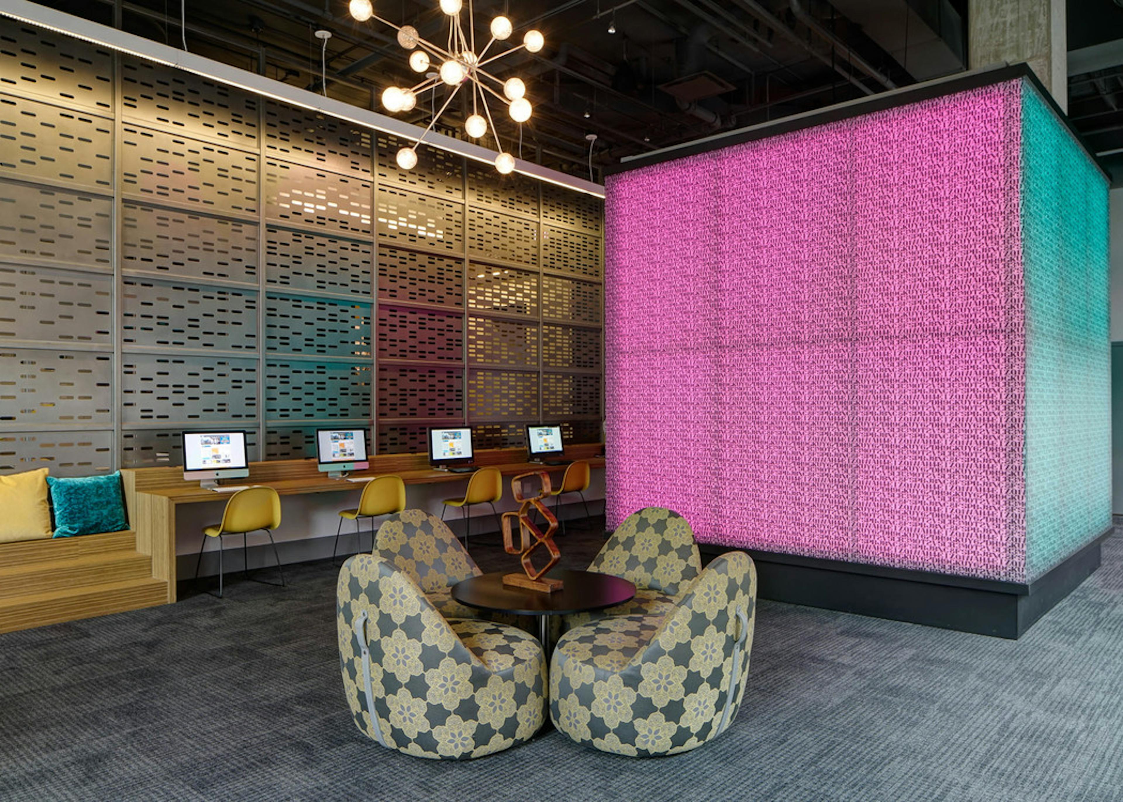 Interior view of the tech lounge at AMLI Lofts with a large pink cube that changes color serving as the focal point