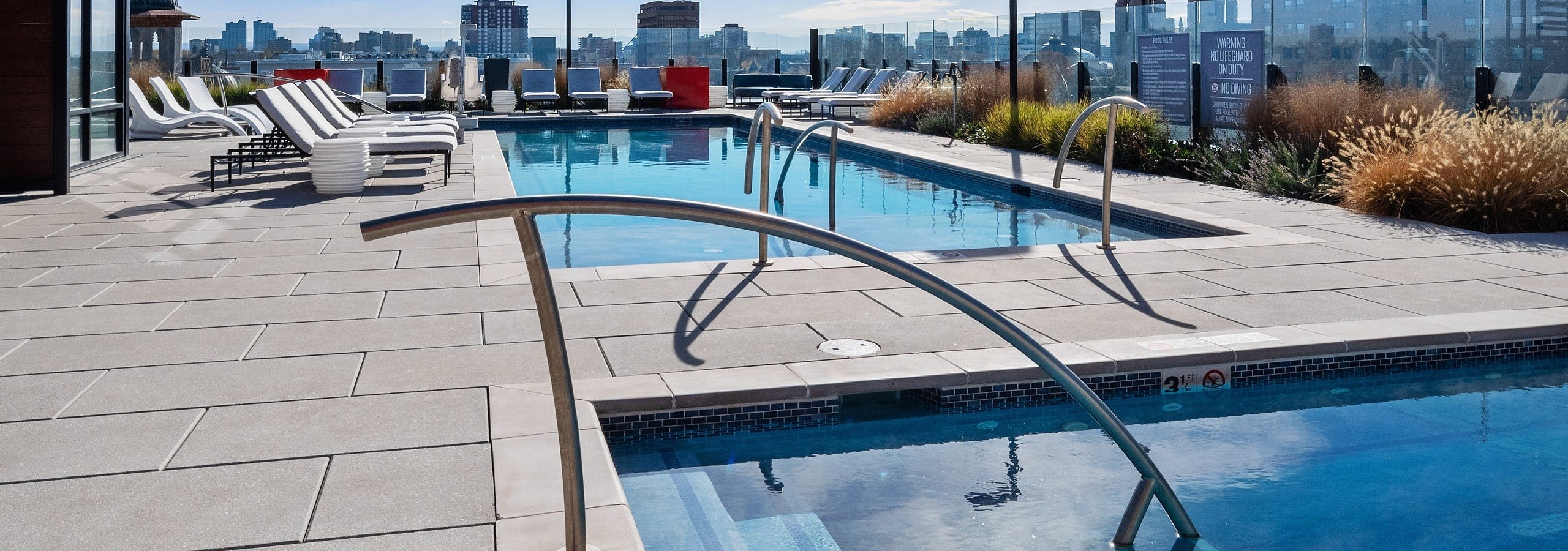 Close up of stairs leading into rooftop spa at AMLI at Uptown apartment community with view of pool in background