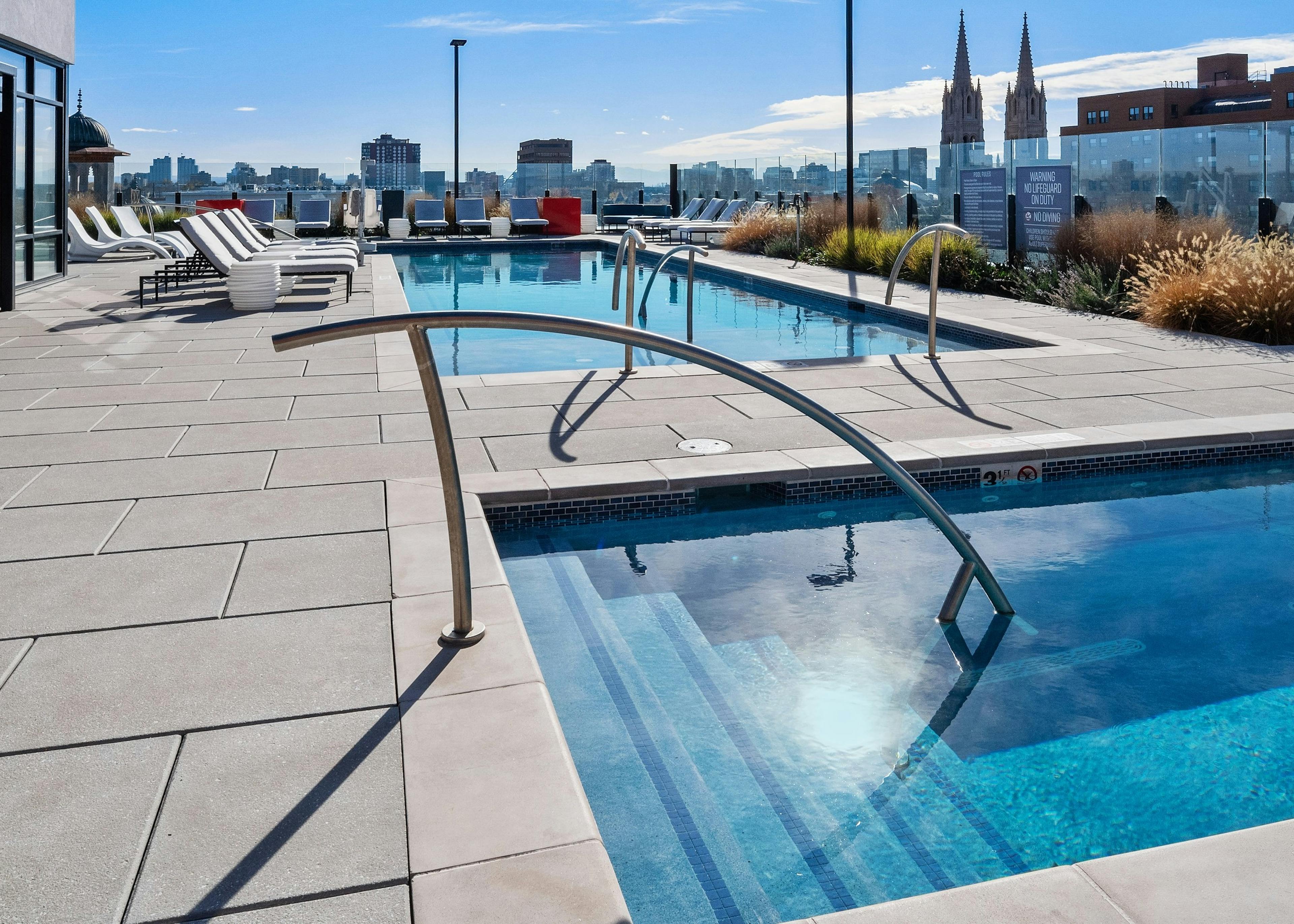 Close up of stairs leading into rooftop spa at AMLI at Uptown apartment community with view of  pool in background