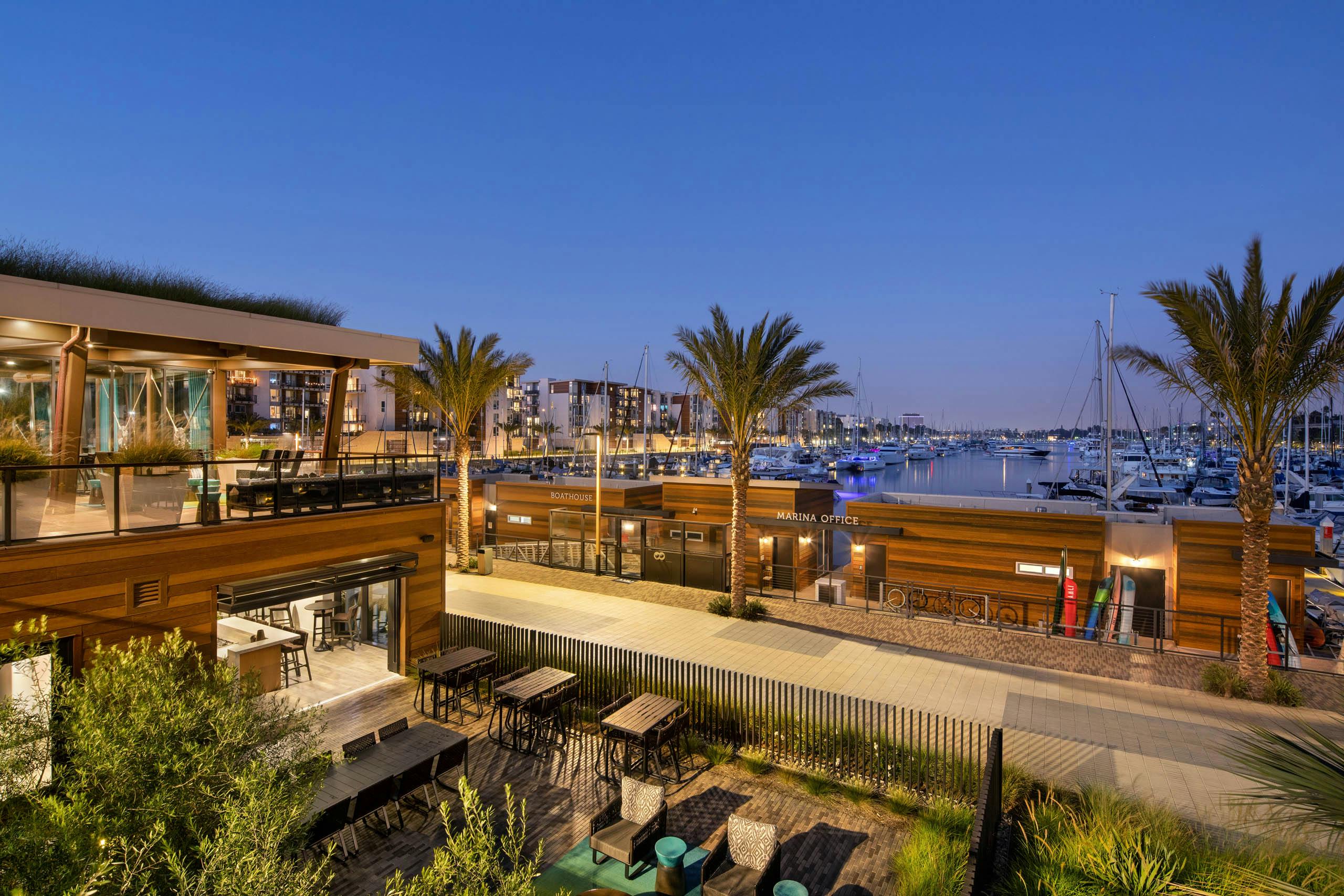 Panoramic evening view of the marina and boats and palm trees and peek into the lit up Jewel building at AMLI Marina Del Rey