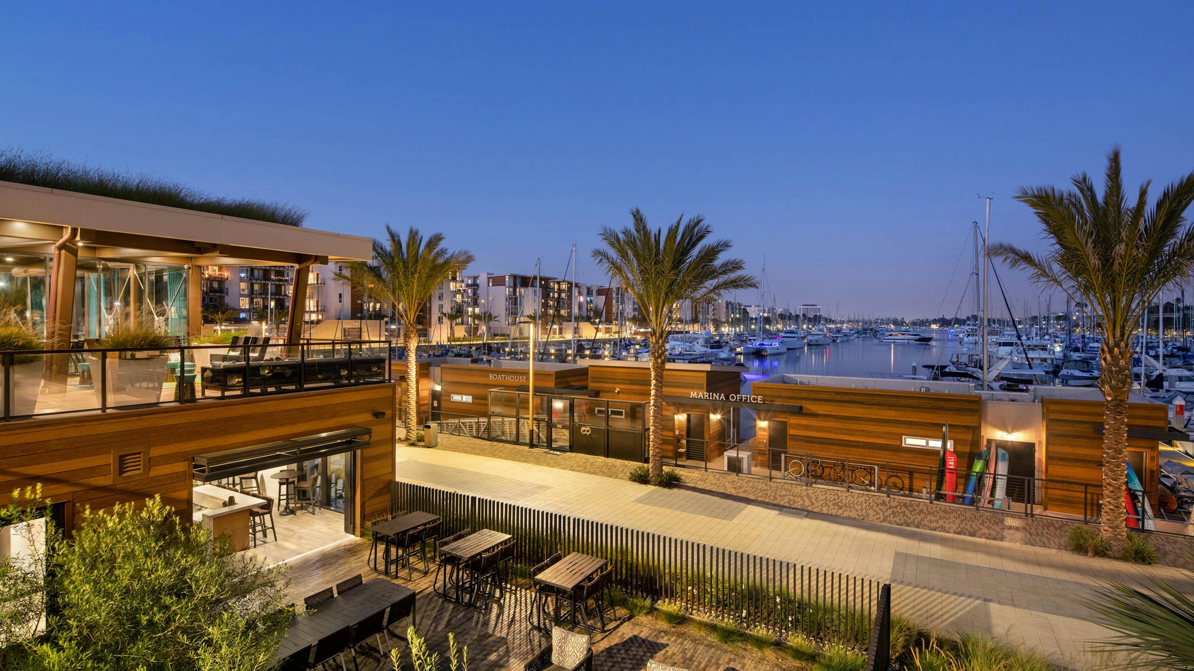 Panoramic evening view of the marina and boats and palm trees and peek into the lit up Jewel building at AMLI Marina Del Rey