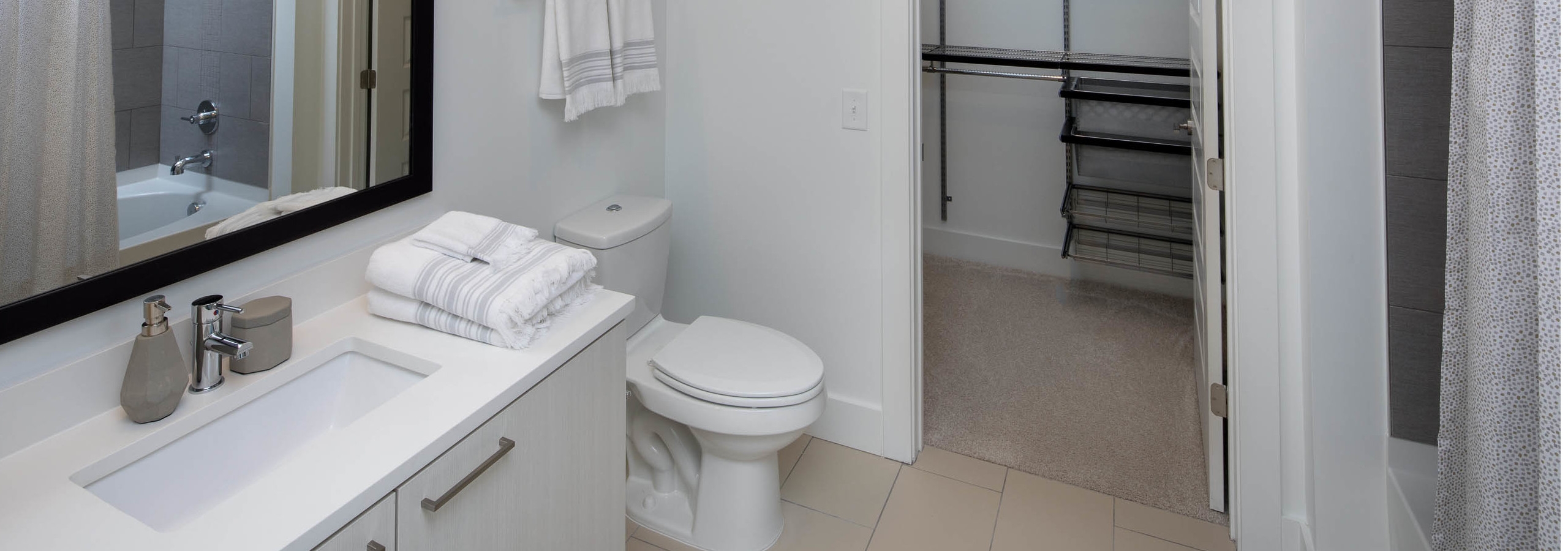 AMLI 3464 bathroom with a white vanity sink and toilet across from the bathtub with an open door peaking into walk in closet