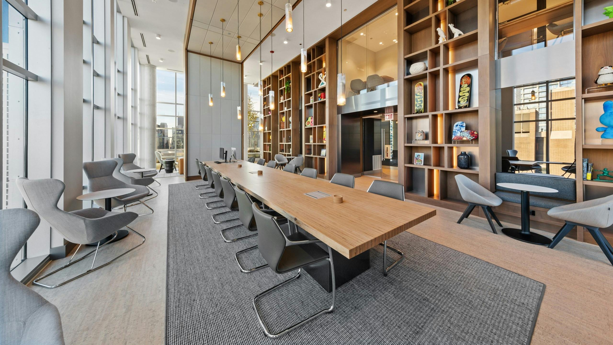 Luxurious collab space amenity at AMLI 808 featuring floor to ceiling windows and a modern table in front of sleek shelving