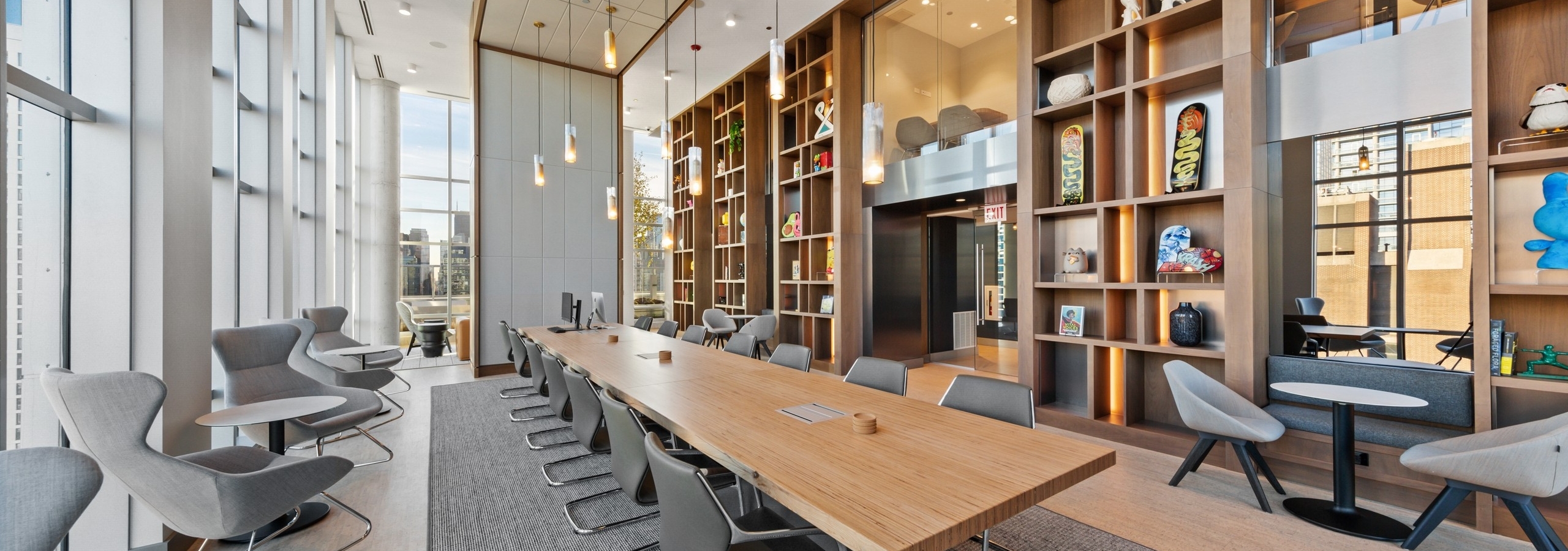 Luxurious collab space amenity at AMLI 808 featuring floor to ceiling windows and a modern table in front of sleek shelving